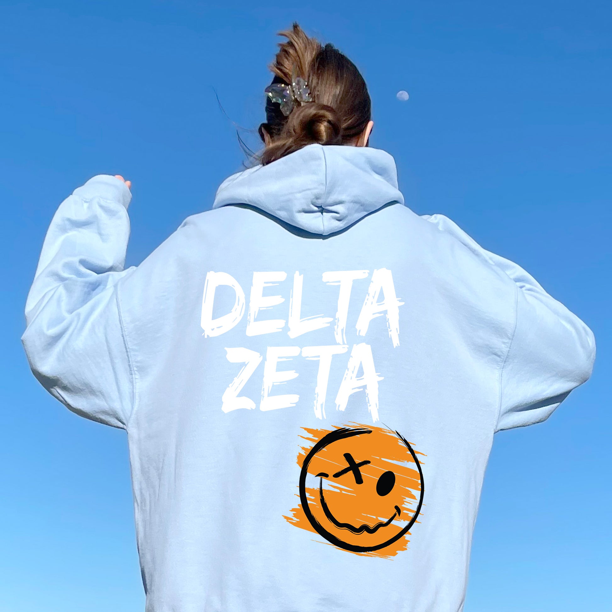 a woman wearing a sweatshirt with the words delta zeta painted on it