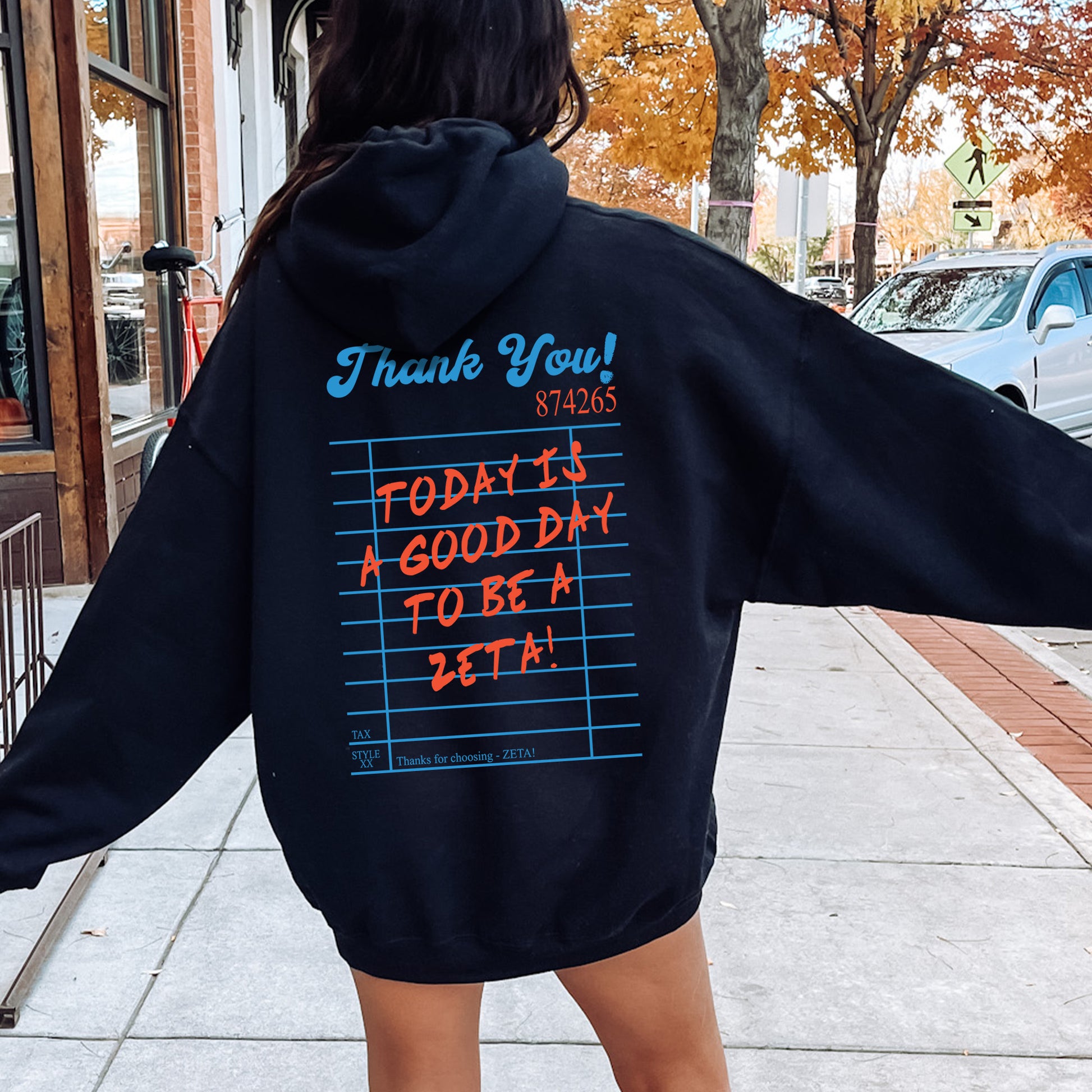 a woman in a black hoodie is walking down the street