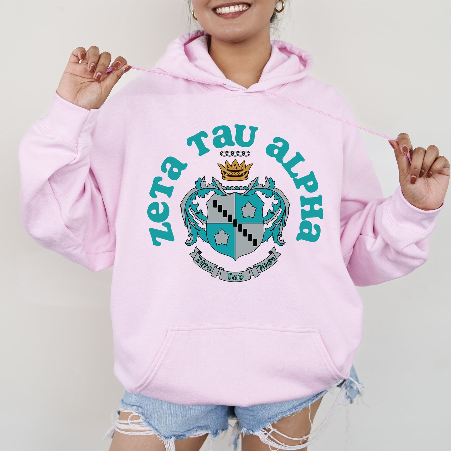 a woman wearing a pink hoodie with a crown on it