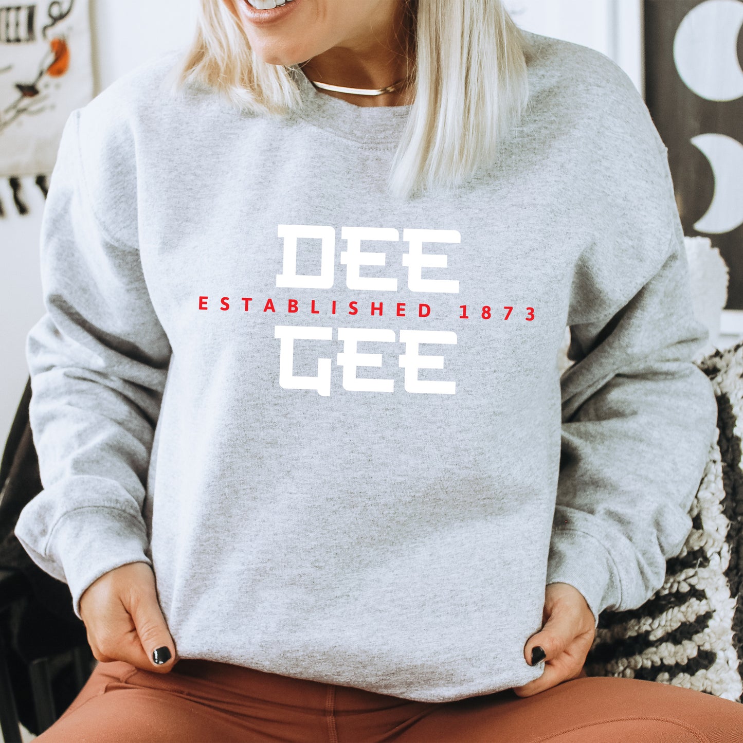 a woman sitting on a chair wearing a grey sweatshirt