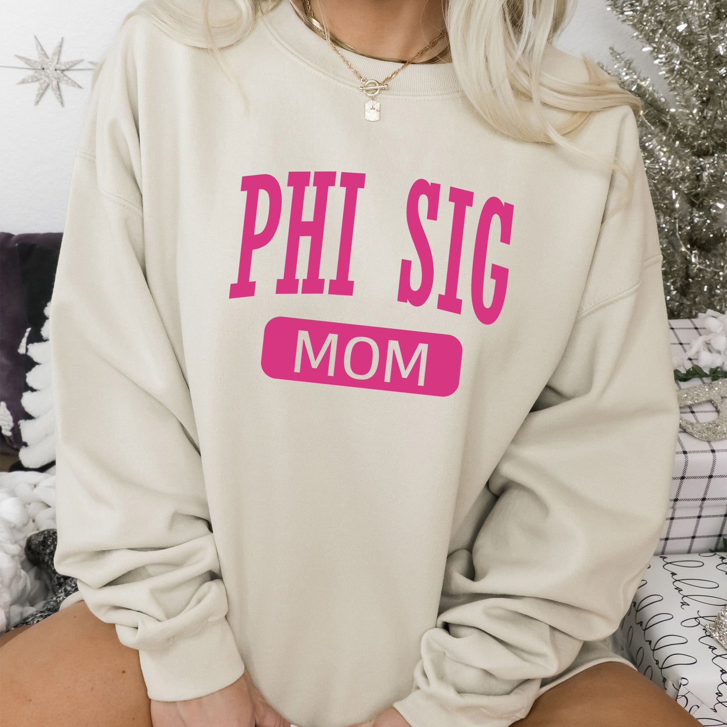 a woman wearing a sweatshirt that says phi sig mom