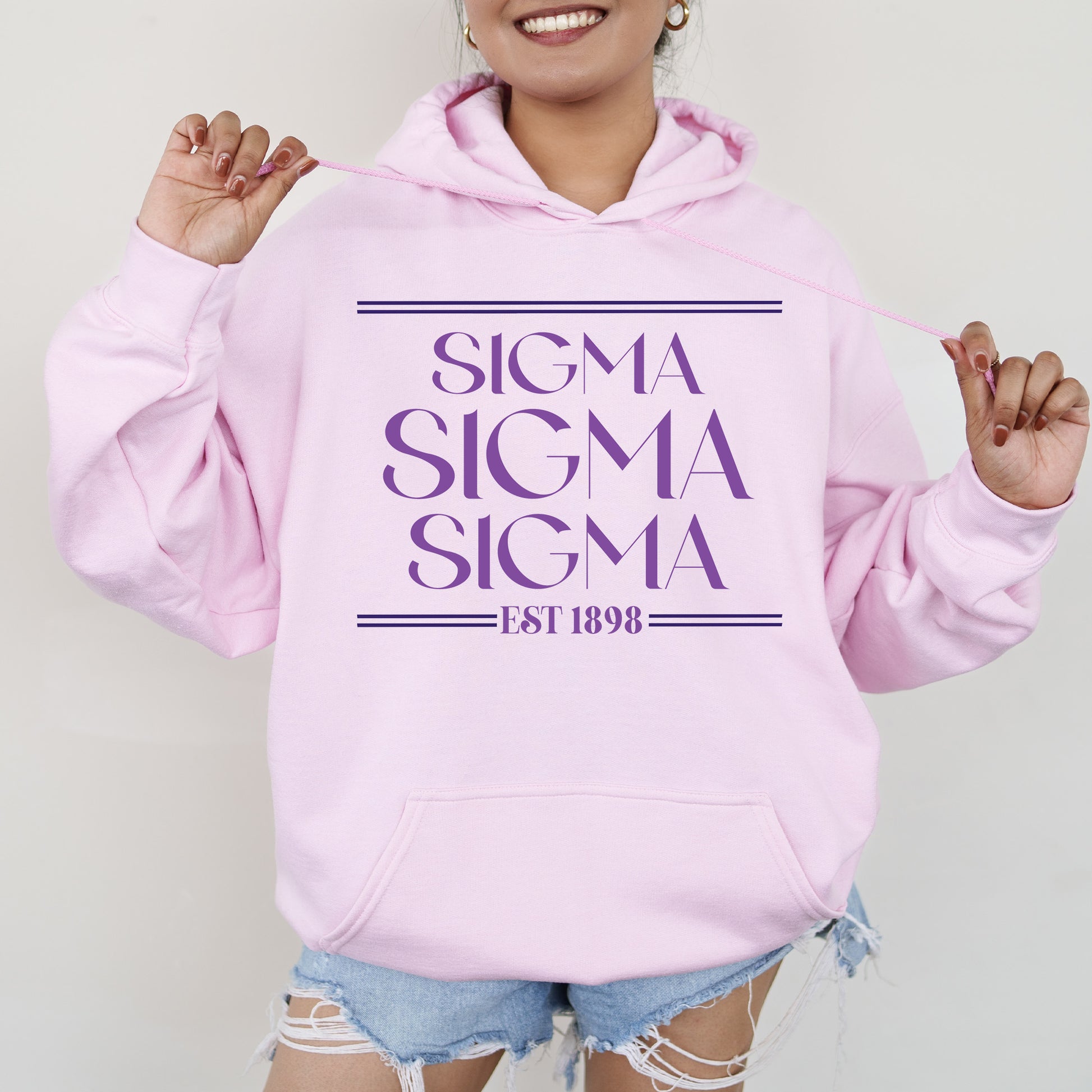 a woman wearing a pink sweatshirt and ripped shorts