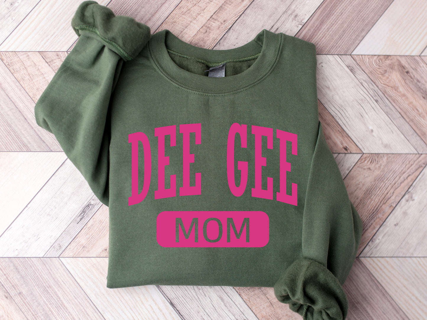 a green sweatshirt with pink lettering that says dee gee mom