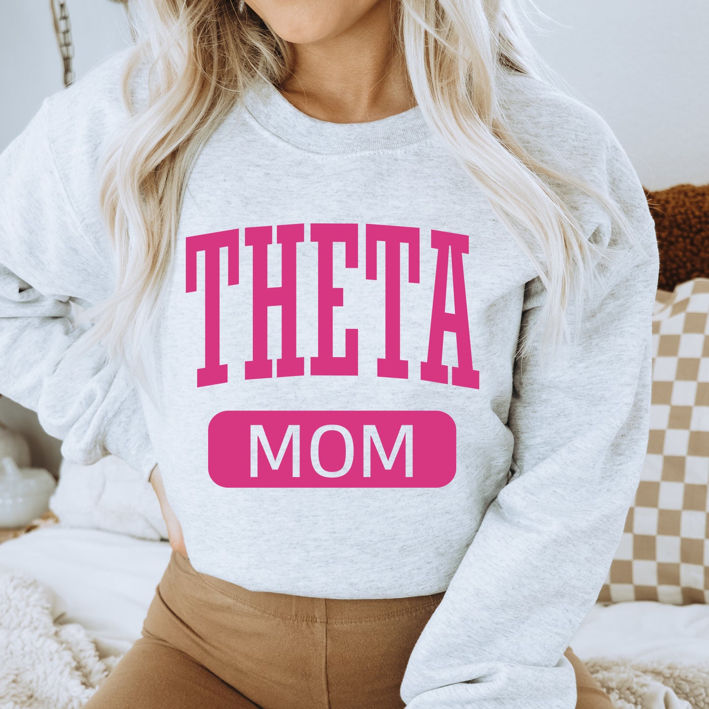 a woman wearing a sweatshirt that says theta mom