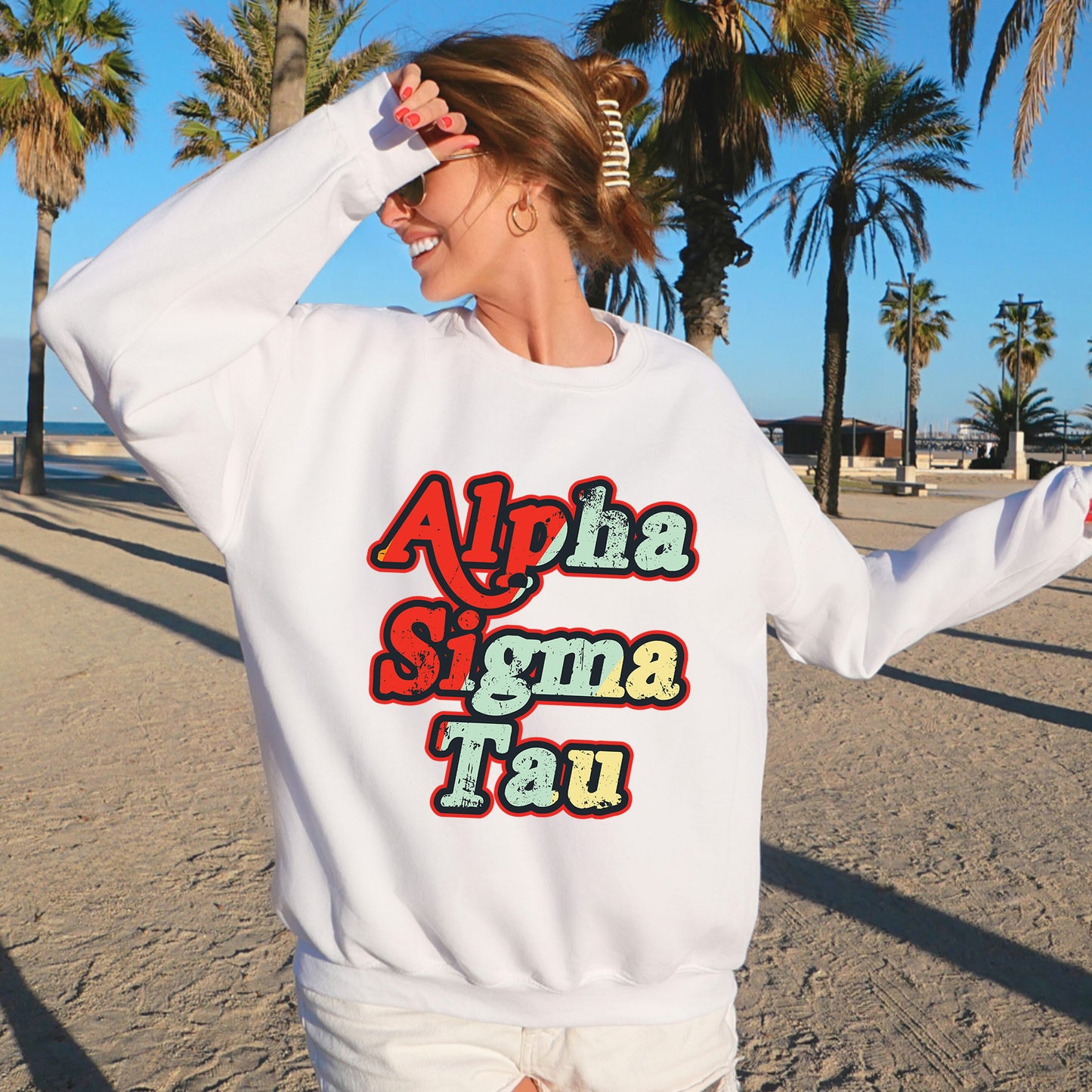 a woman standing on a beach wearing a white sweatshirt