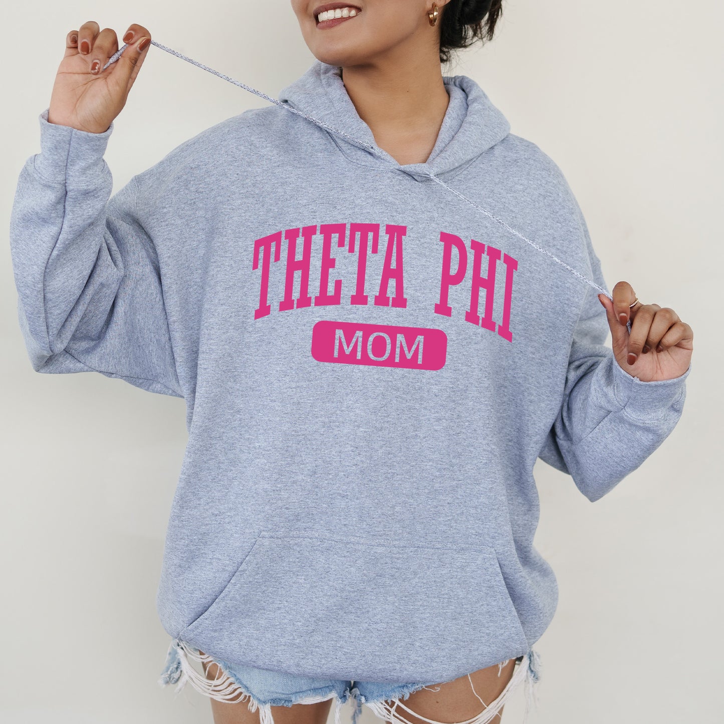 a woman wearing a sweatshirt that says thea phi mom
