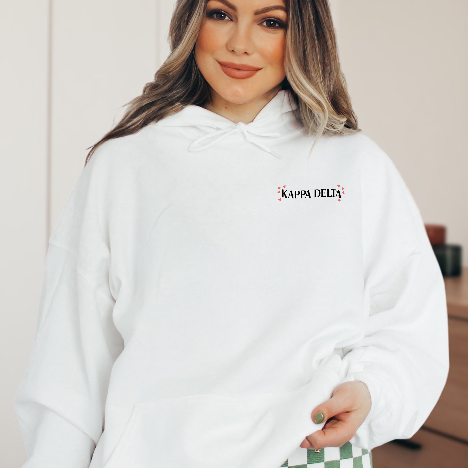 a woman wearing a white hoodie with a checkerboard print on the side