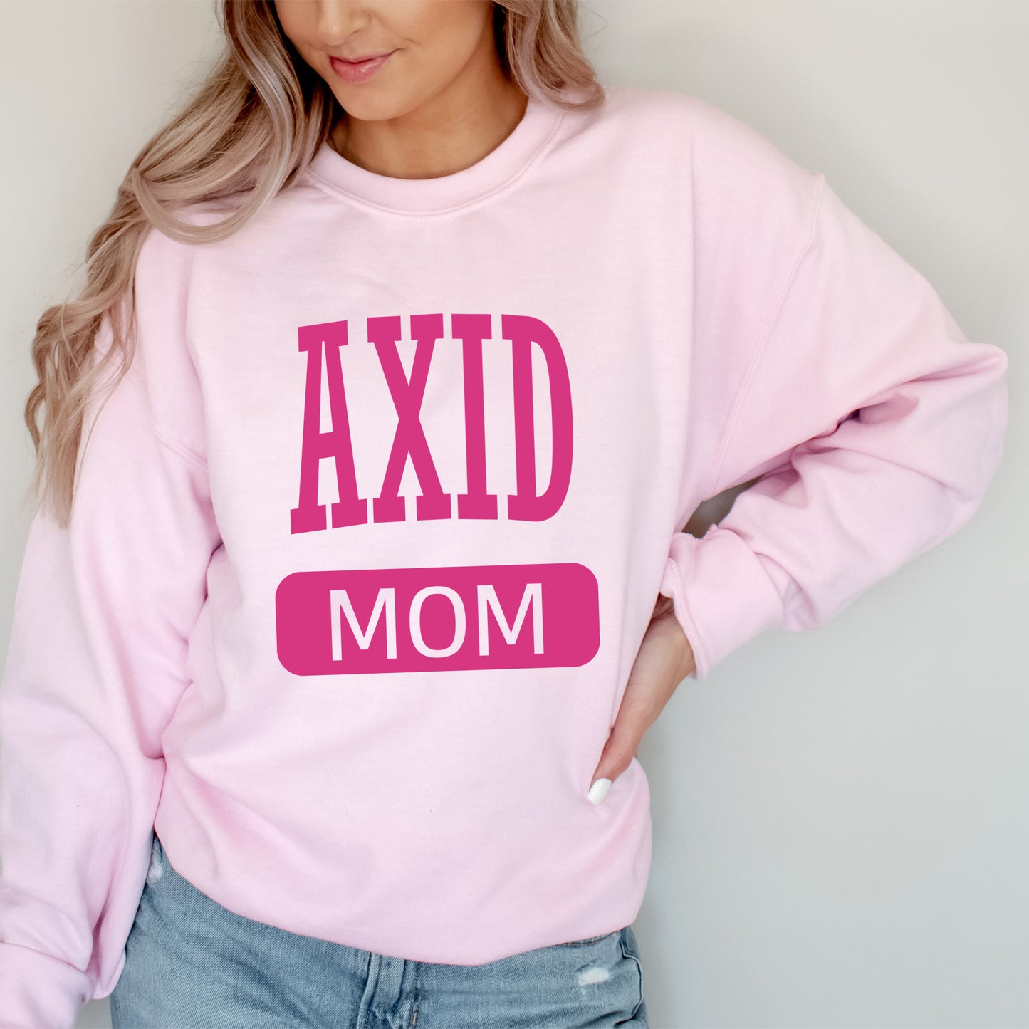 a woman wearing a pink sweatshirt that says axd mom