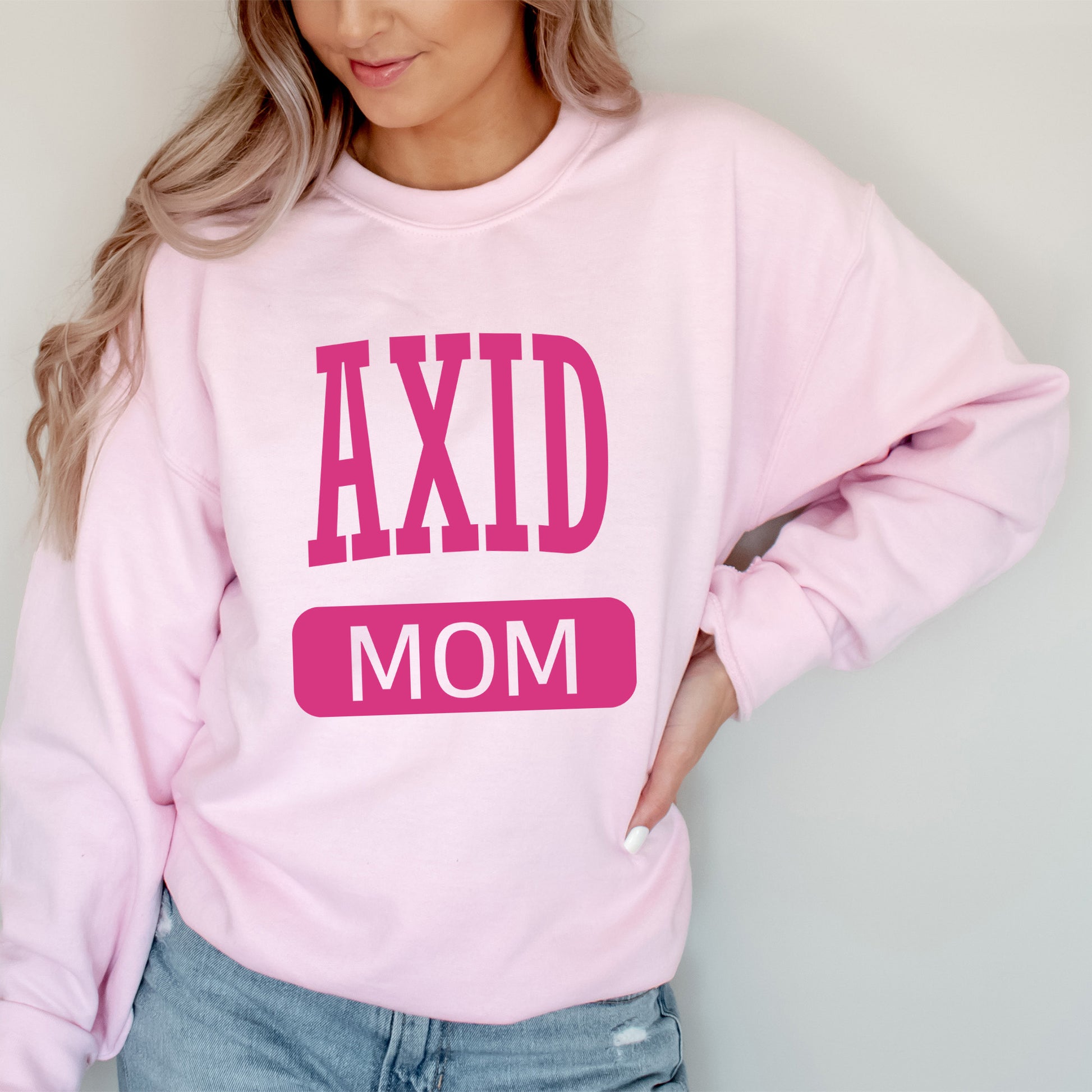 a woman wearing a pink sweatshirt that says axd mom