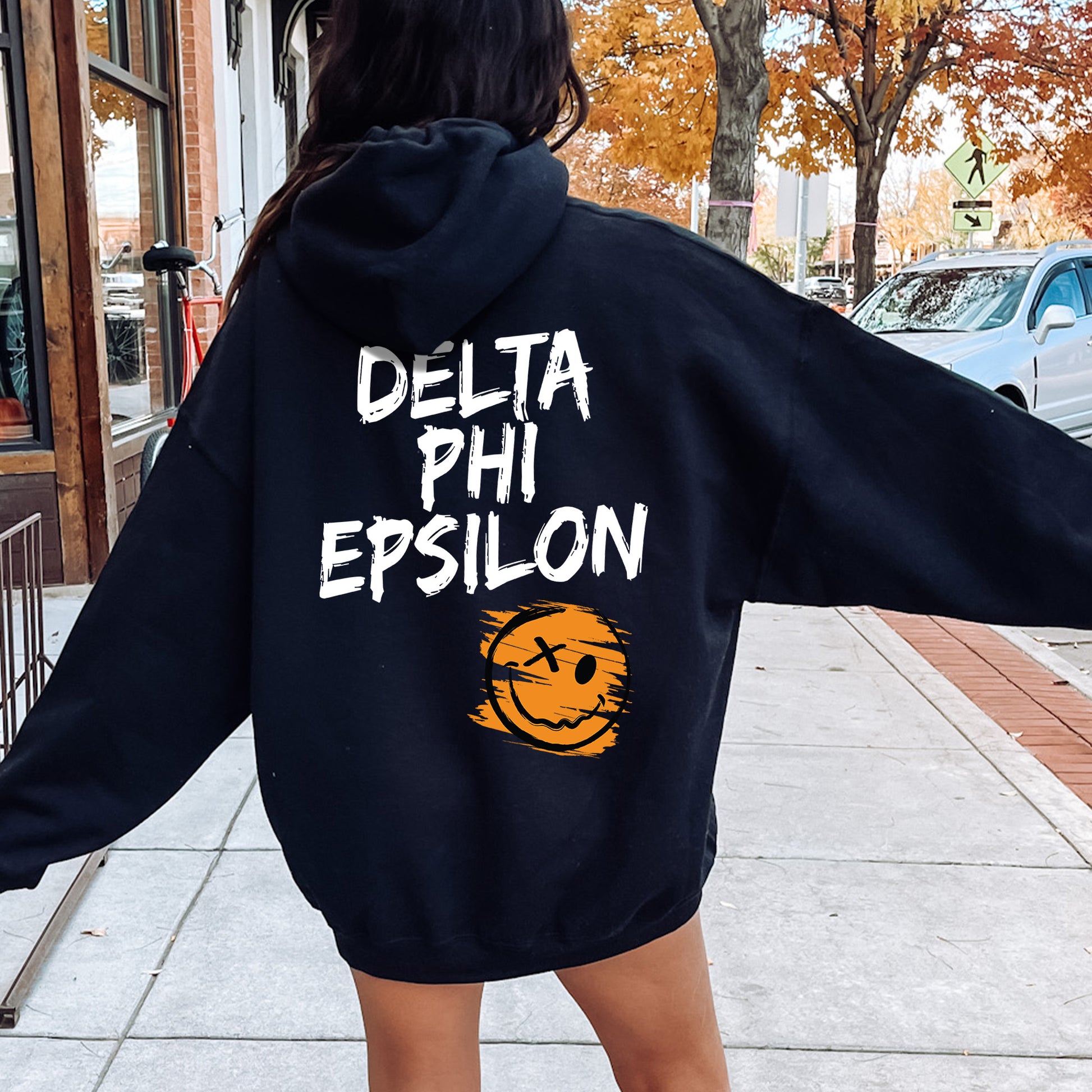 a woman walking down a sidewalk wearing a black sweatshirt