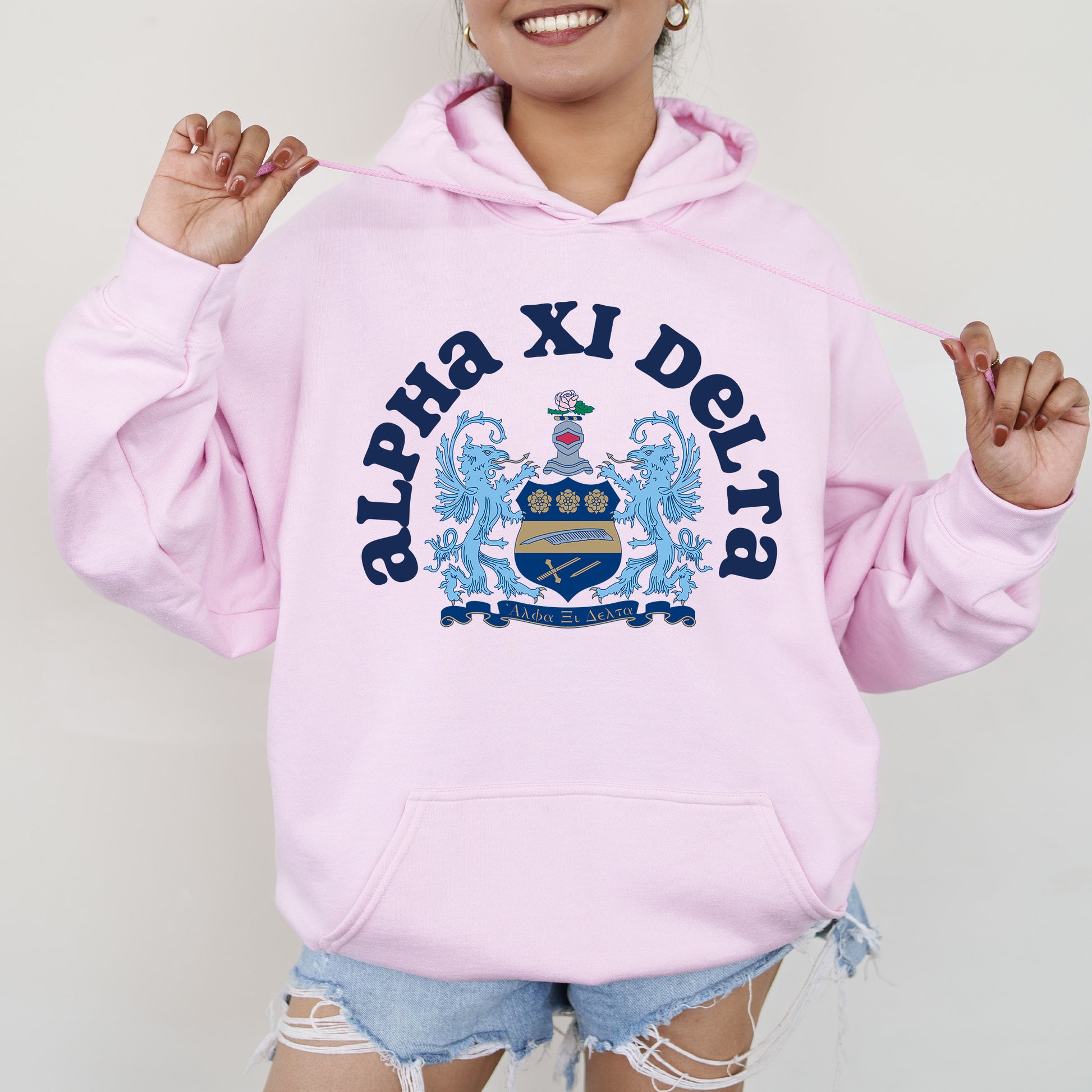 a woman wearing a pink hoodie with a coat of arms on it