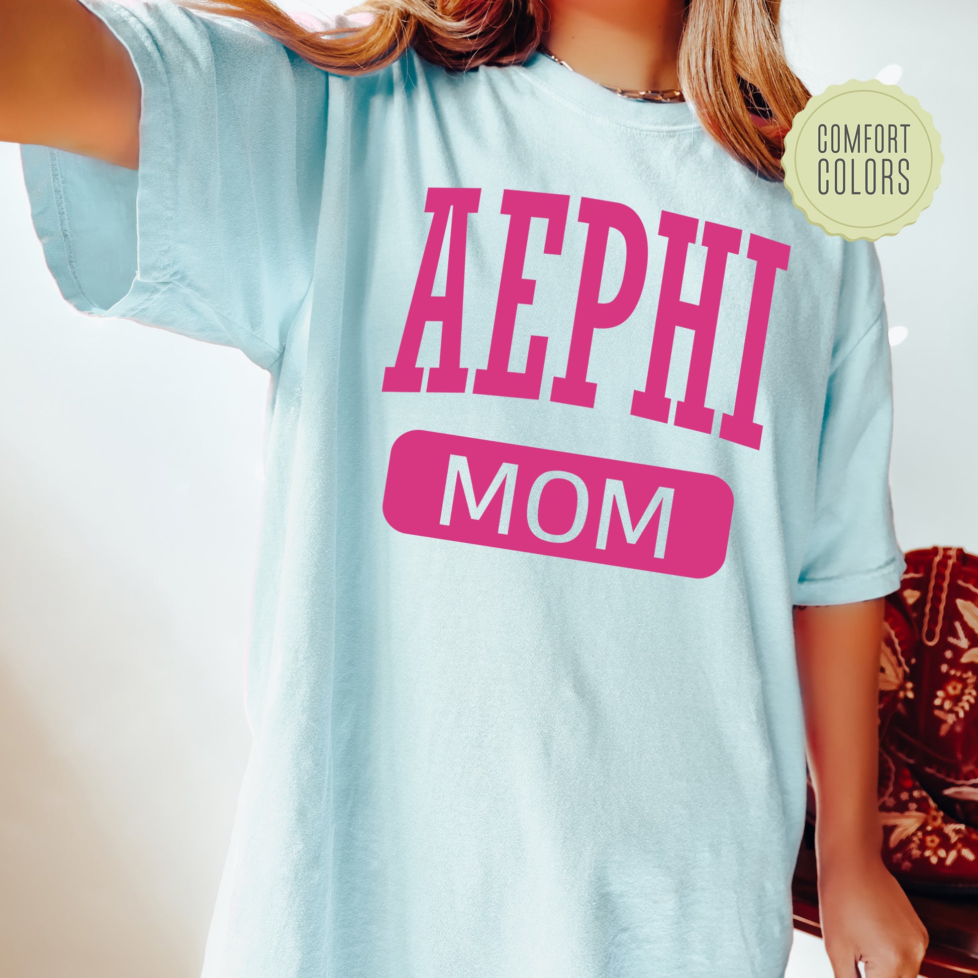 a woman wearing a light blue shirt that says aephi mom