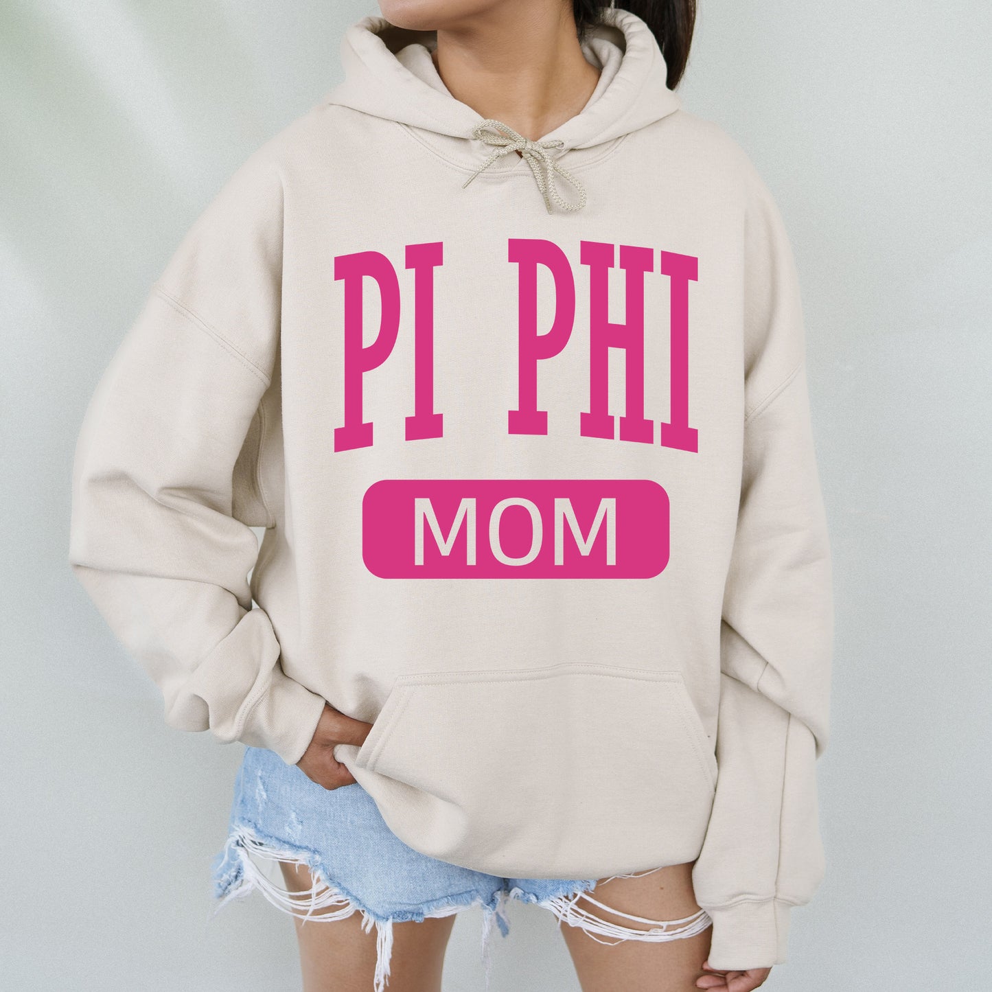 a woman wearing a sweatshirt that says pi phi mom