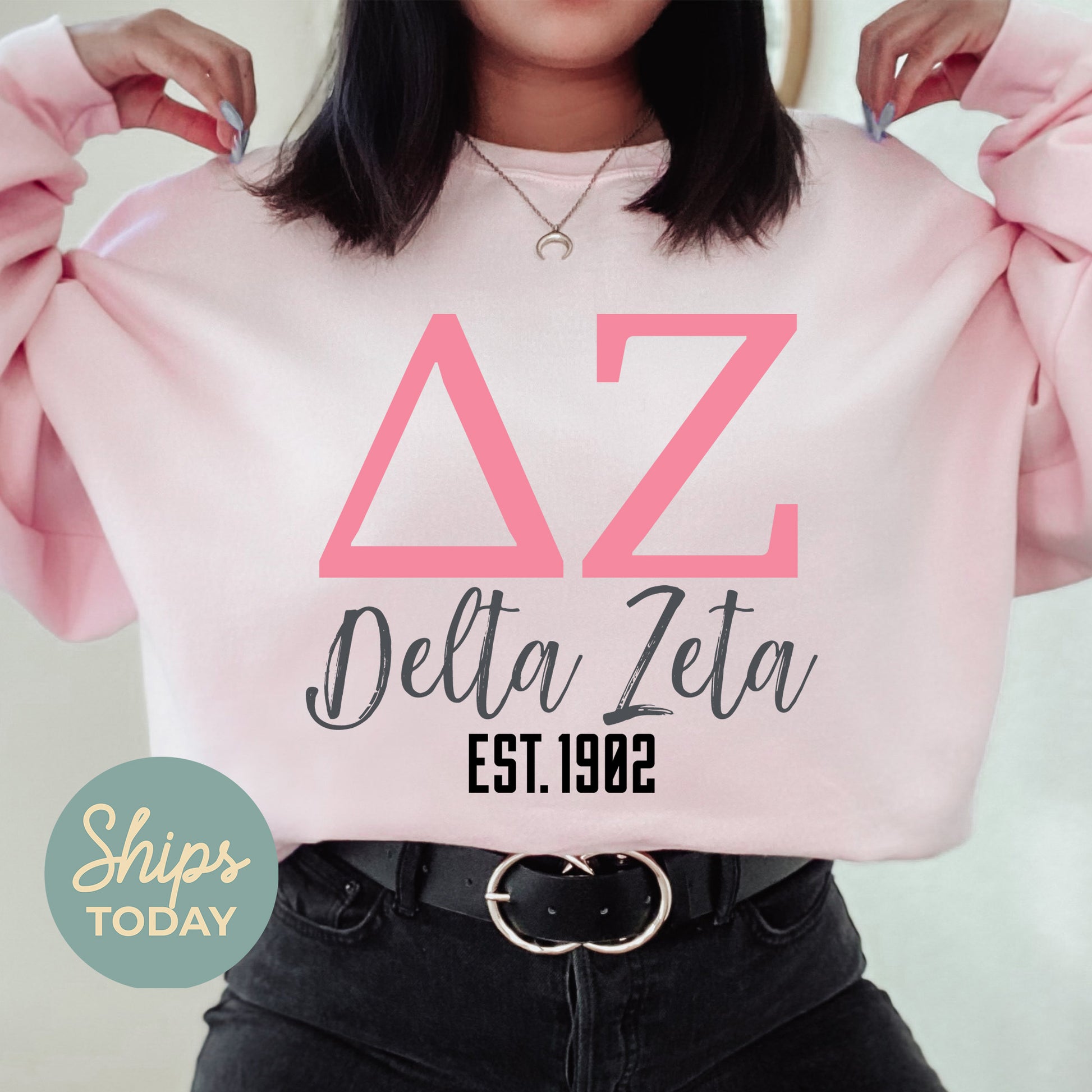 a woman wearing a pink sweatshirt with the letters delta delta on it