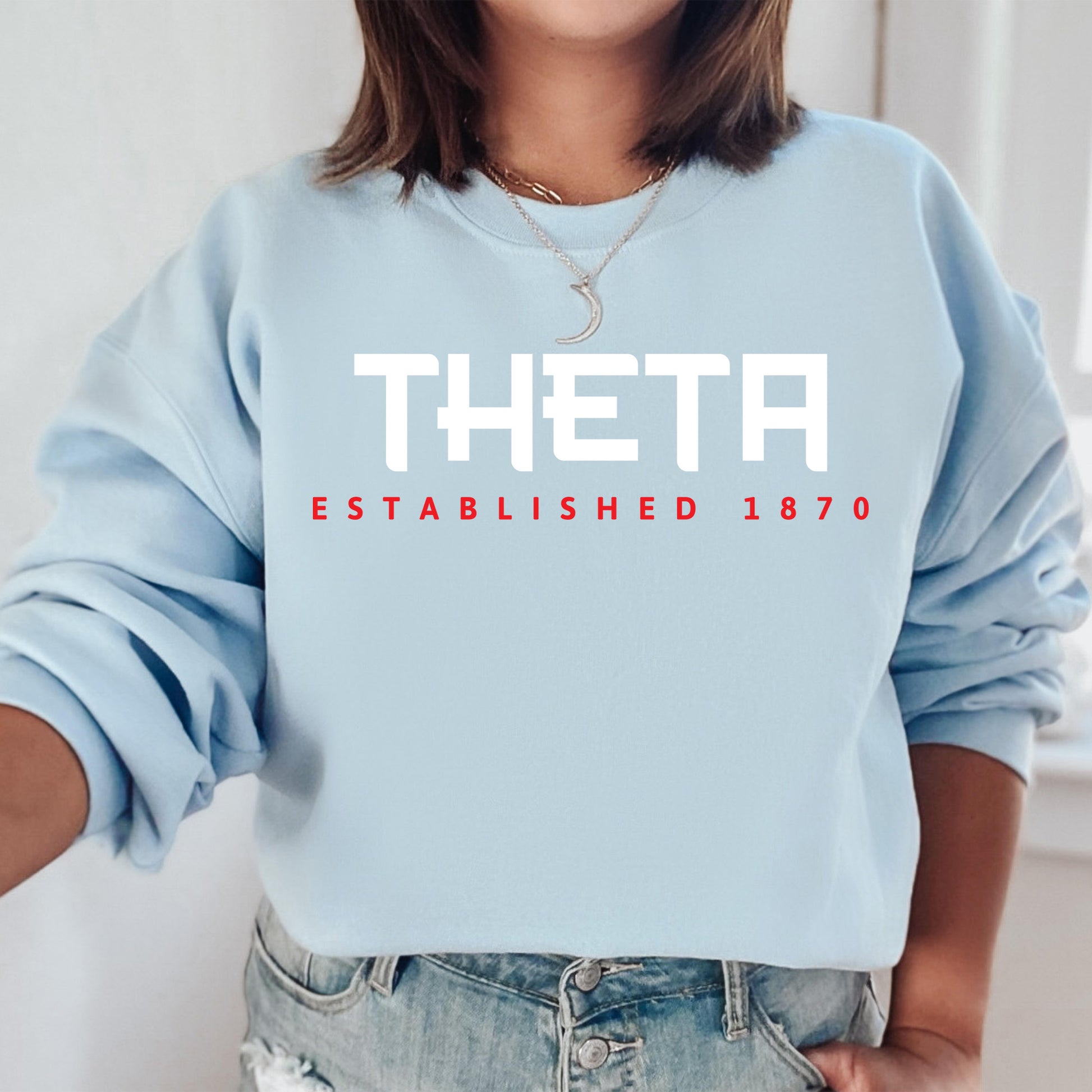 a woman wearing a sweatshirt that says theta established 1970