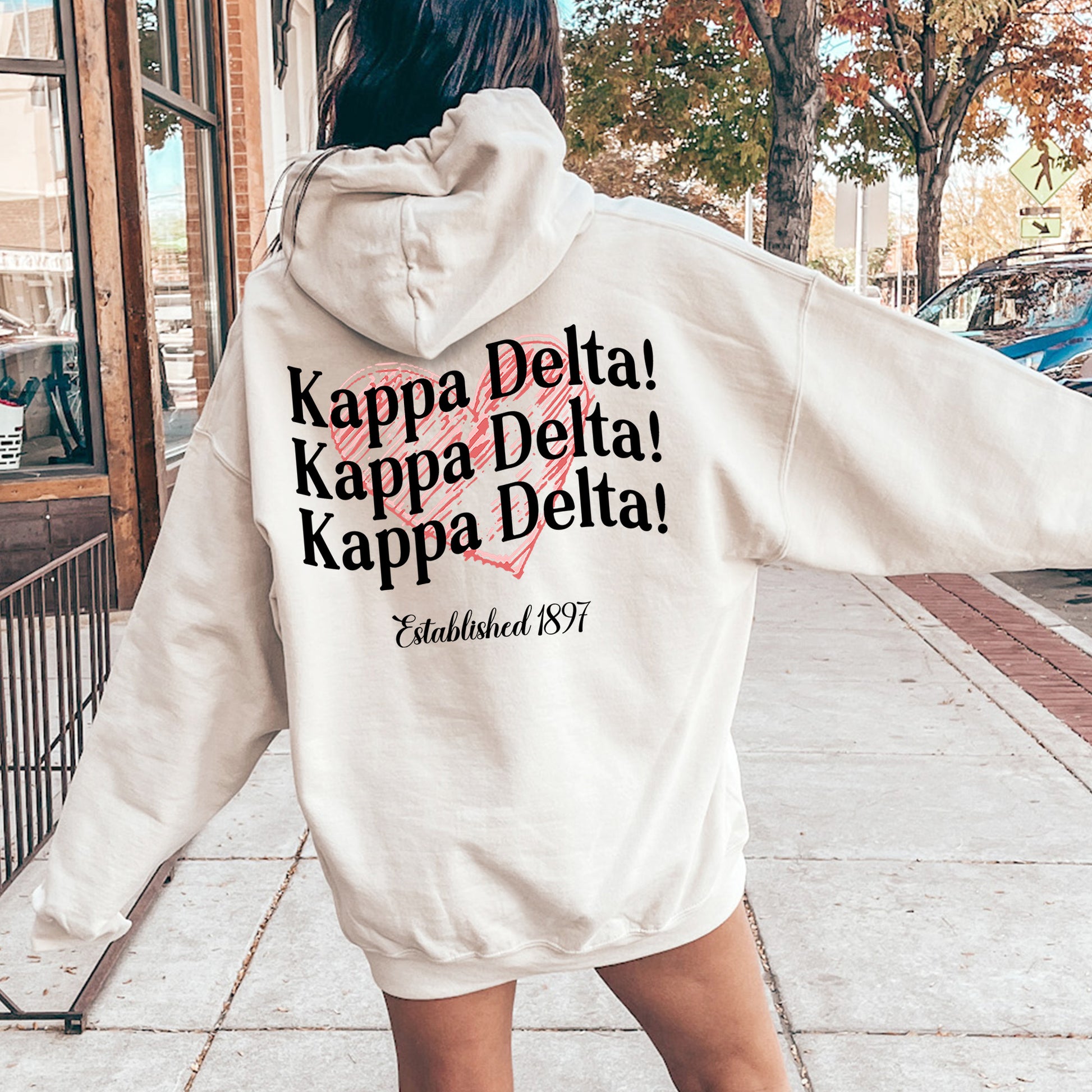 a woman in a white hoodie is walking down the street