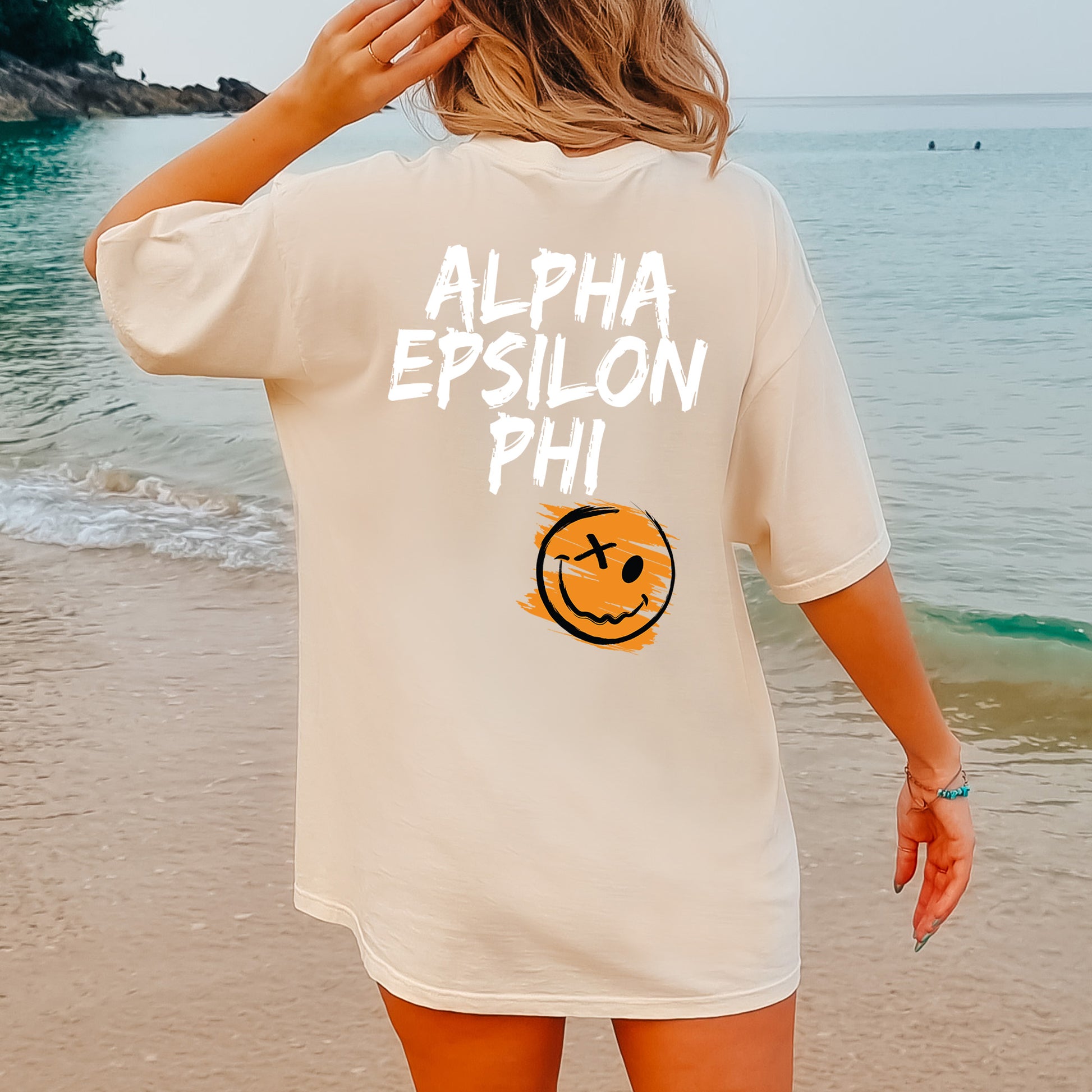 a woman standing on a beach wearing a white shirt