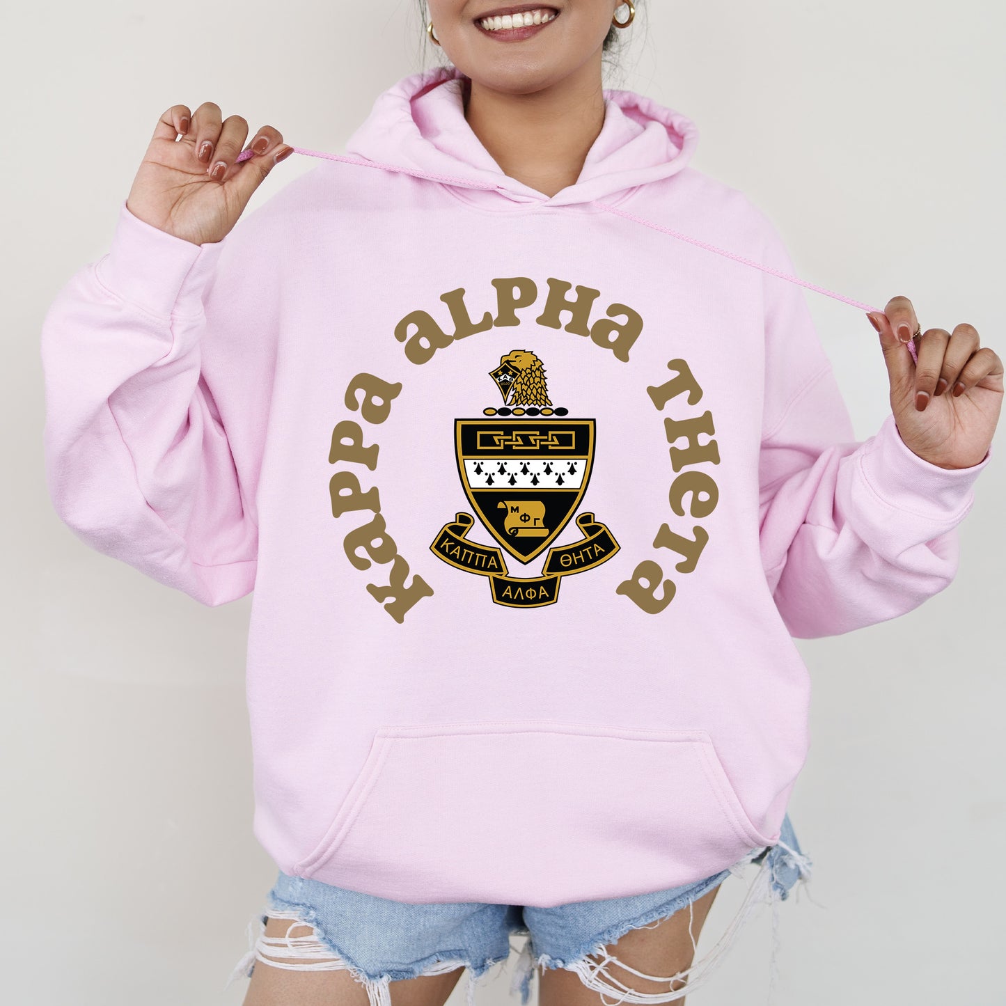 a young woman wearing a pink hoodie with a crest on it