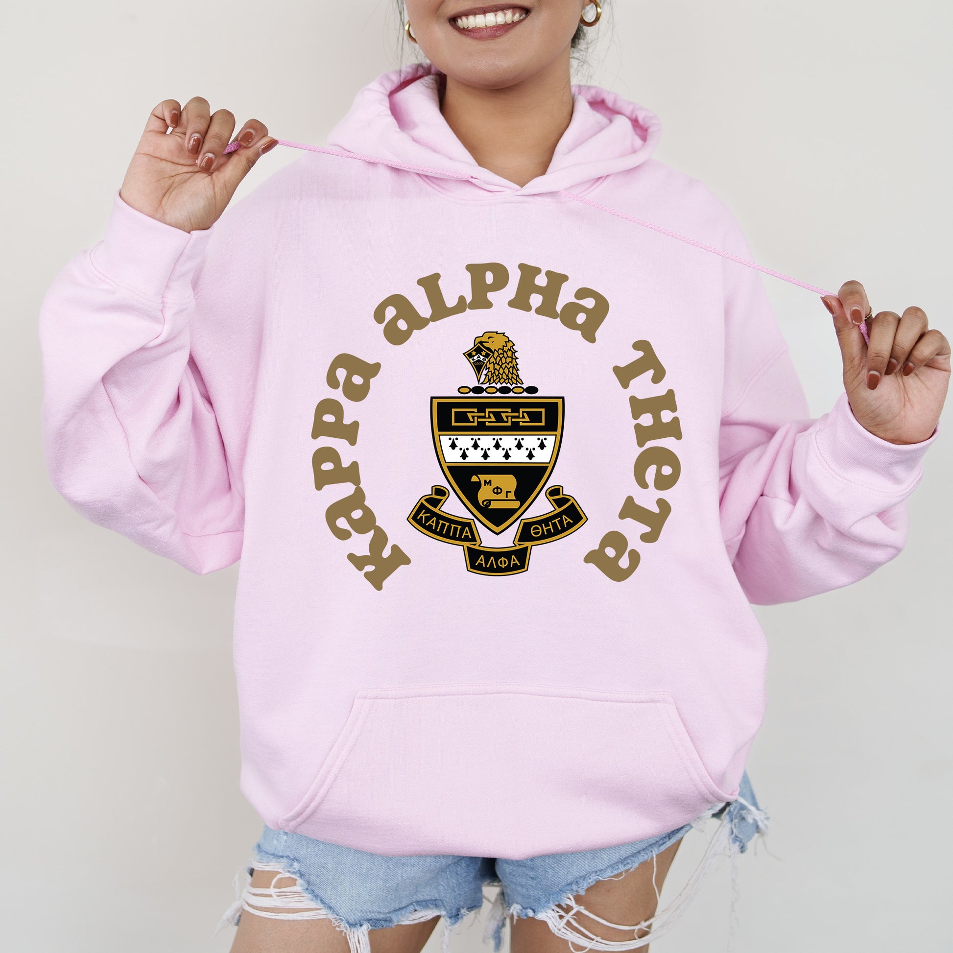 a young woman wearing a pink hoodie with a crest on it