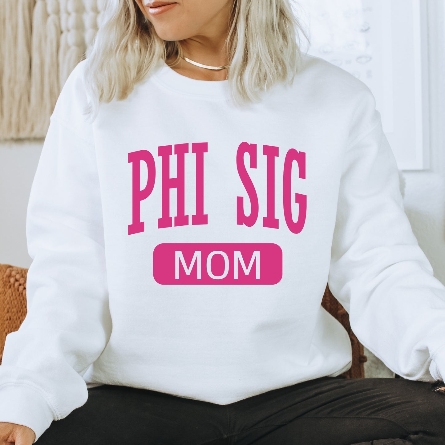 a woman wearing a sweatshirt that says phi sig mom
