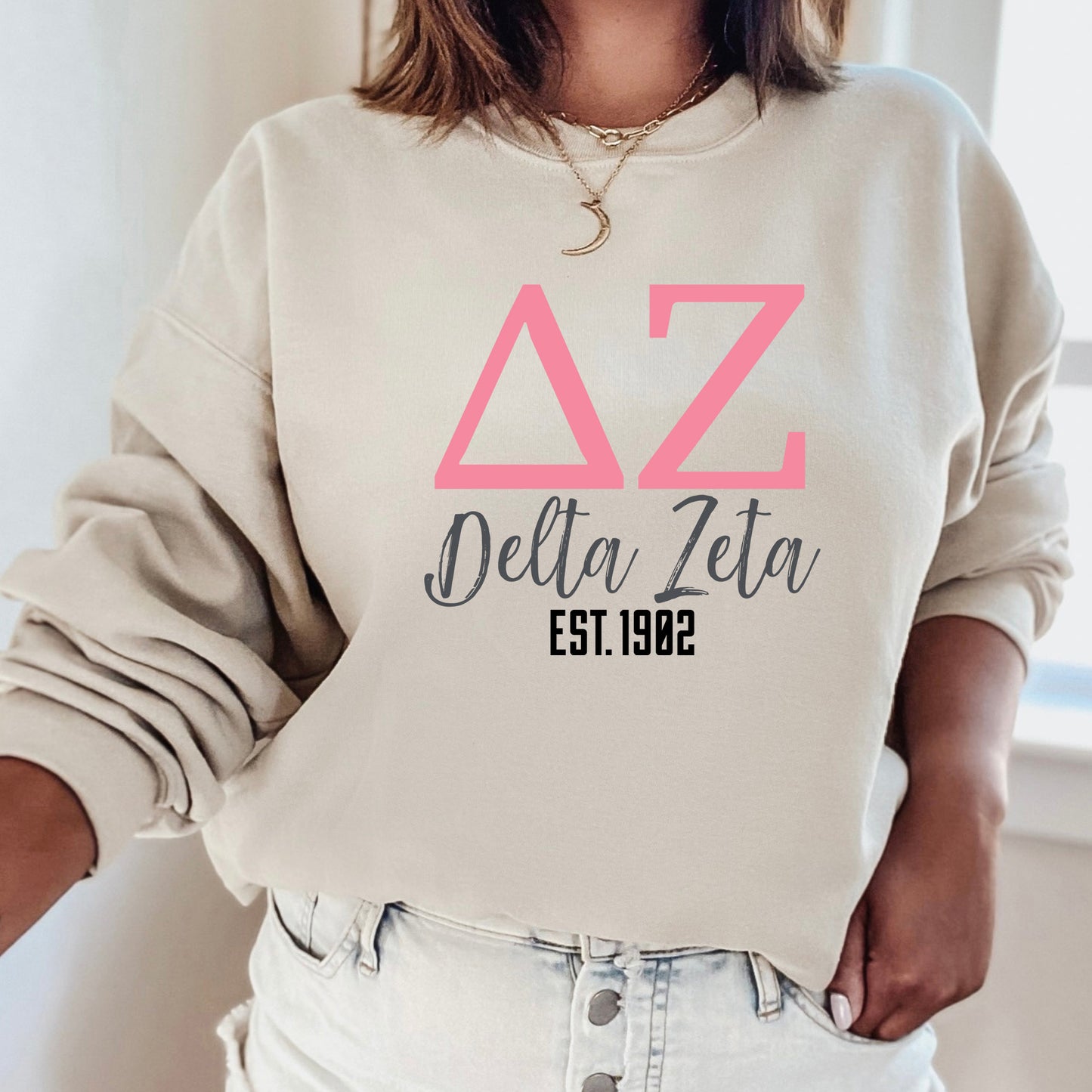 a woman wearing a delta delta sweatshirt and jeans