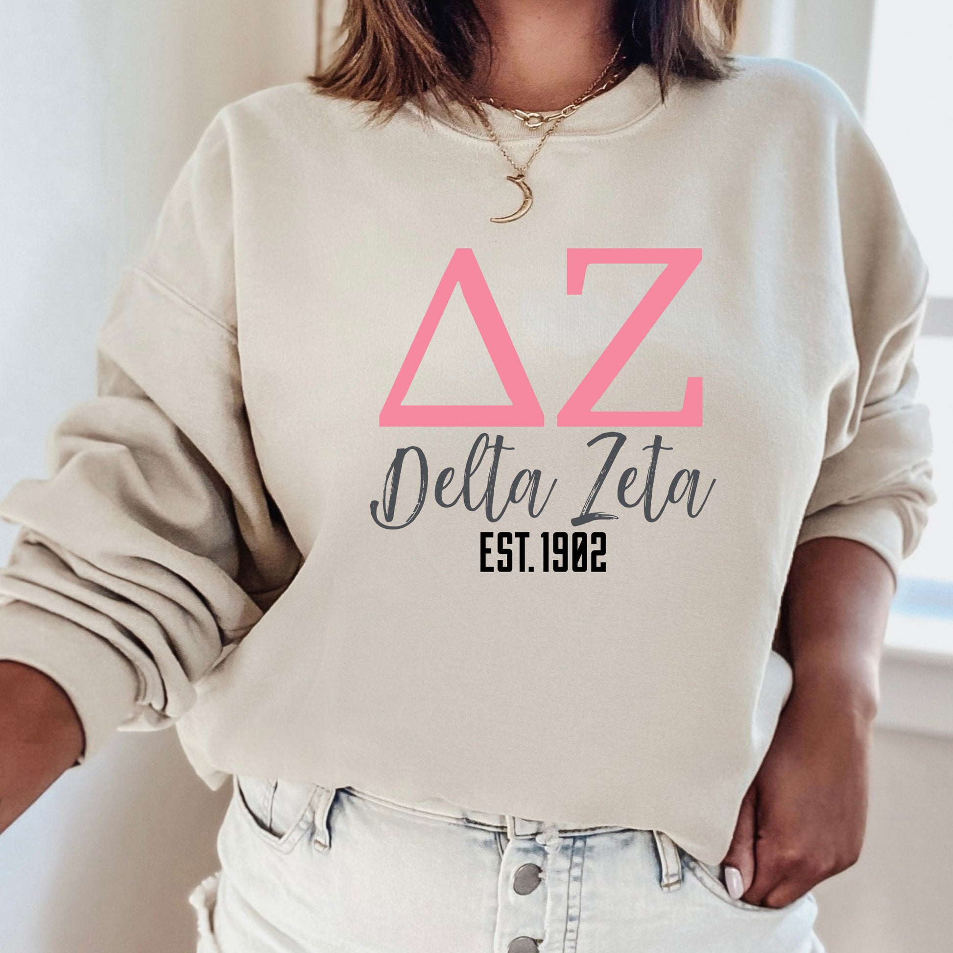 a woman wearing a delta delta sweatshirt and jeans