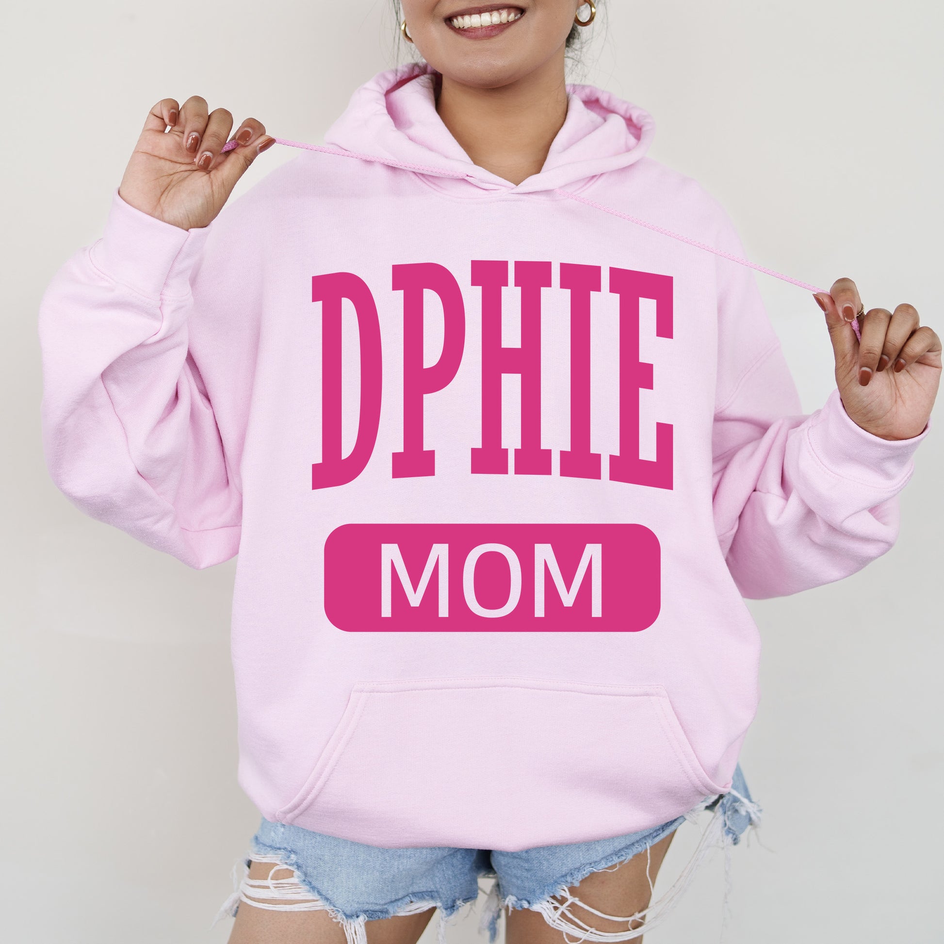 a woman wearing a pink hoodie with the word dppie mom on it