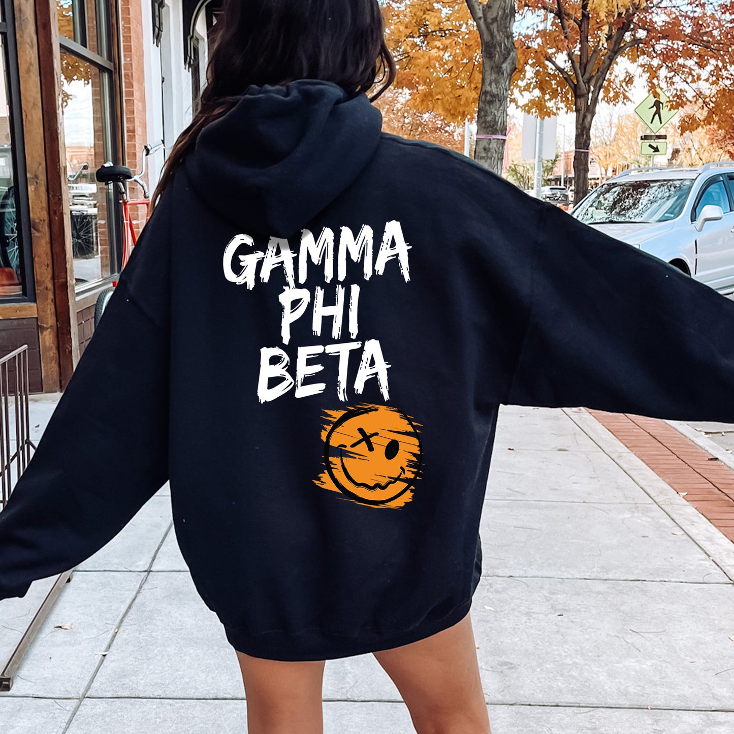 a woman in a black hoodie is walking down the street