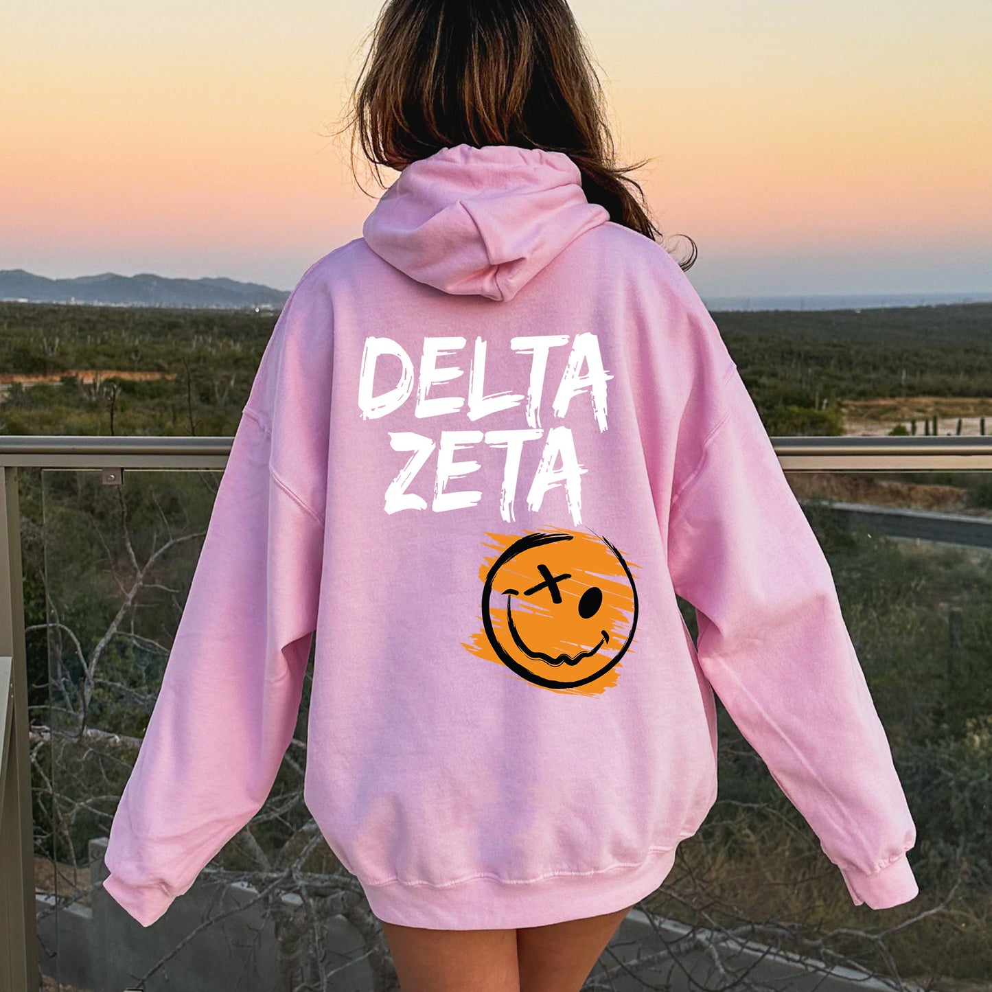a girl wearing a pink sweatshirt with a smiley face on it