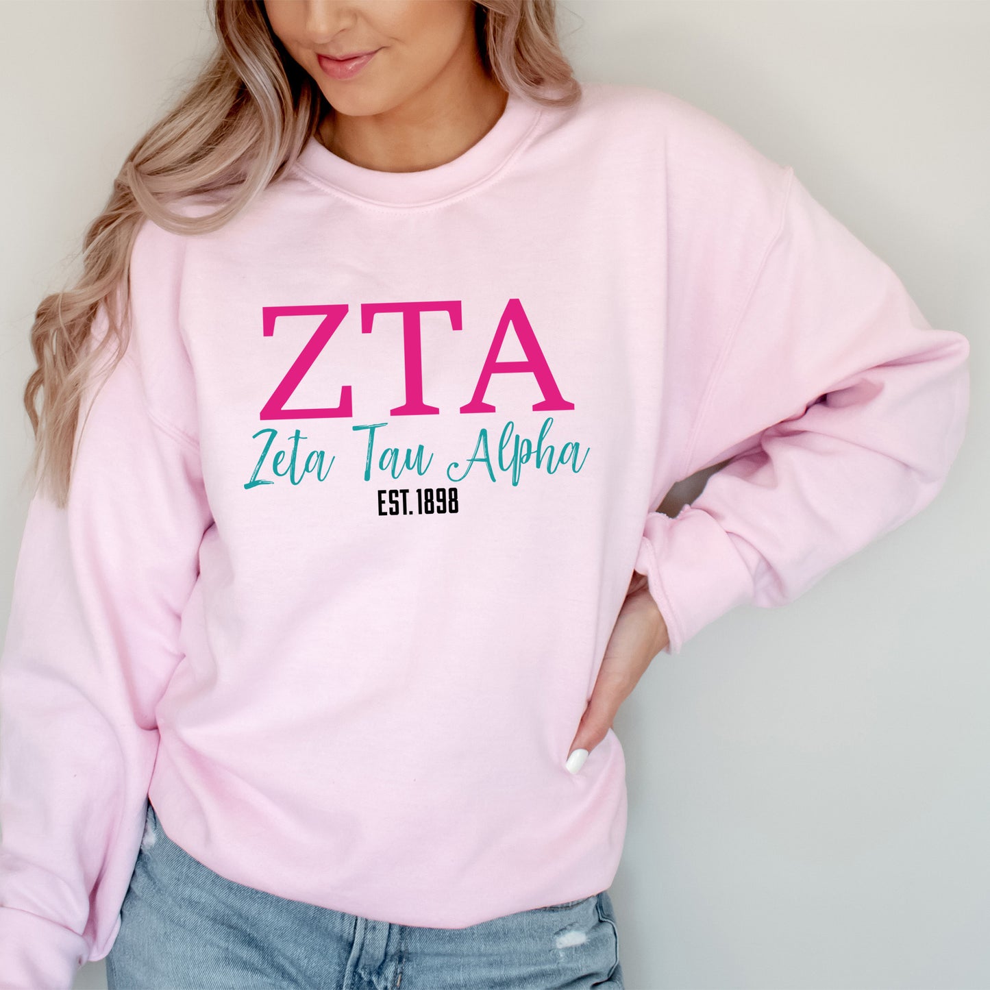 a woman wearing a pink sweater with a pink zta on it