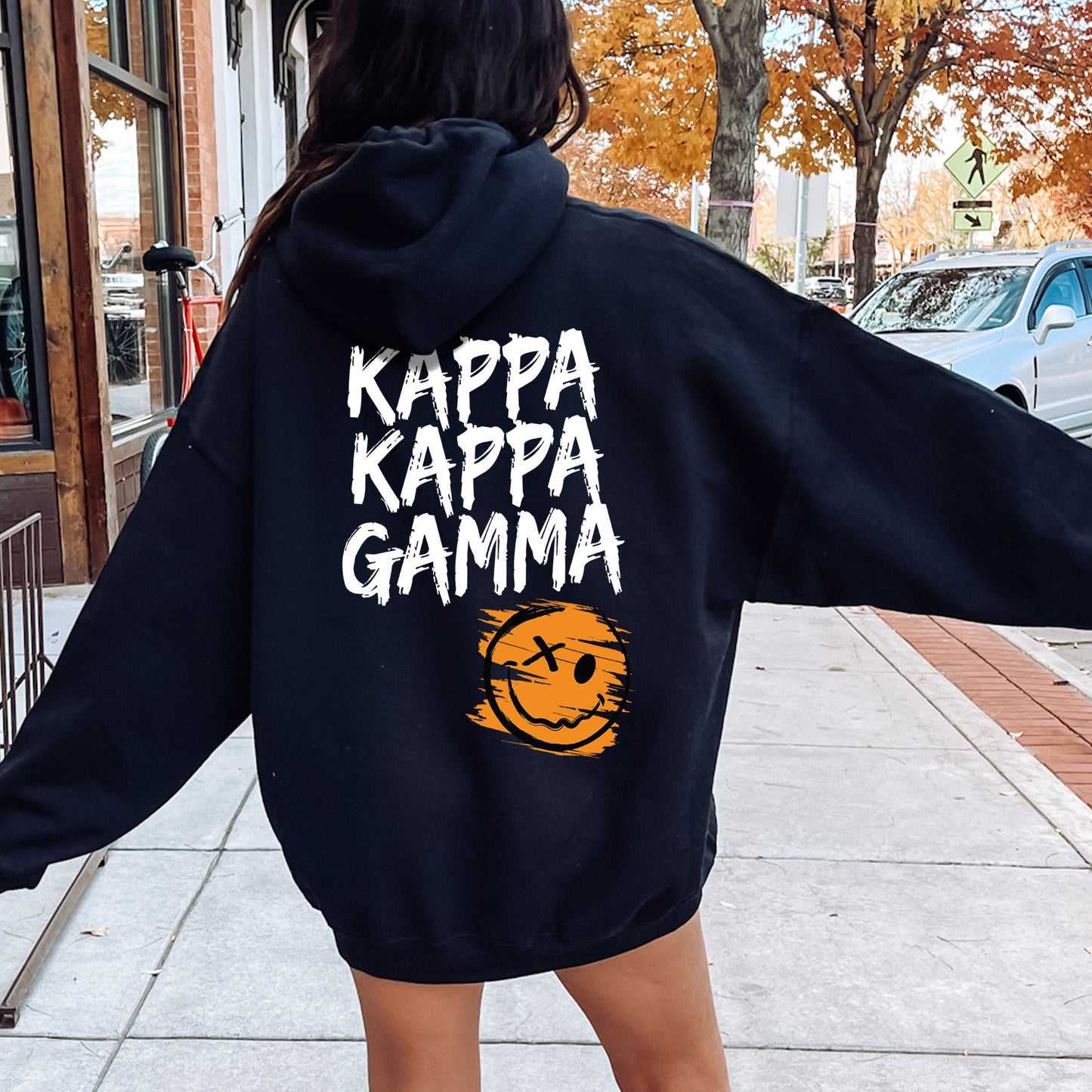 a woman in a black hoodie is walking down the street