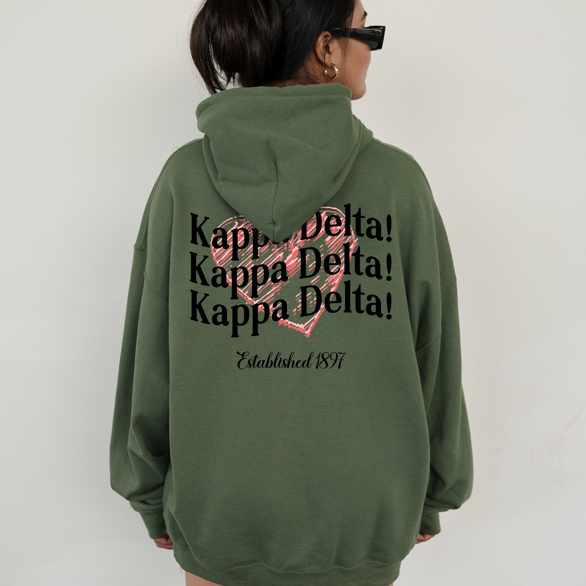 a woman wearing a green hoodie with a pink heart on it