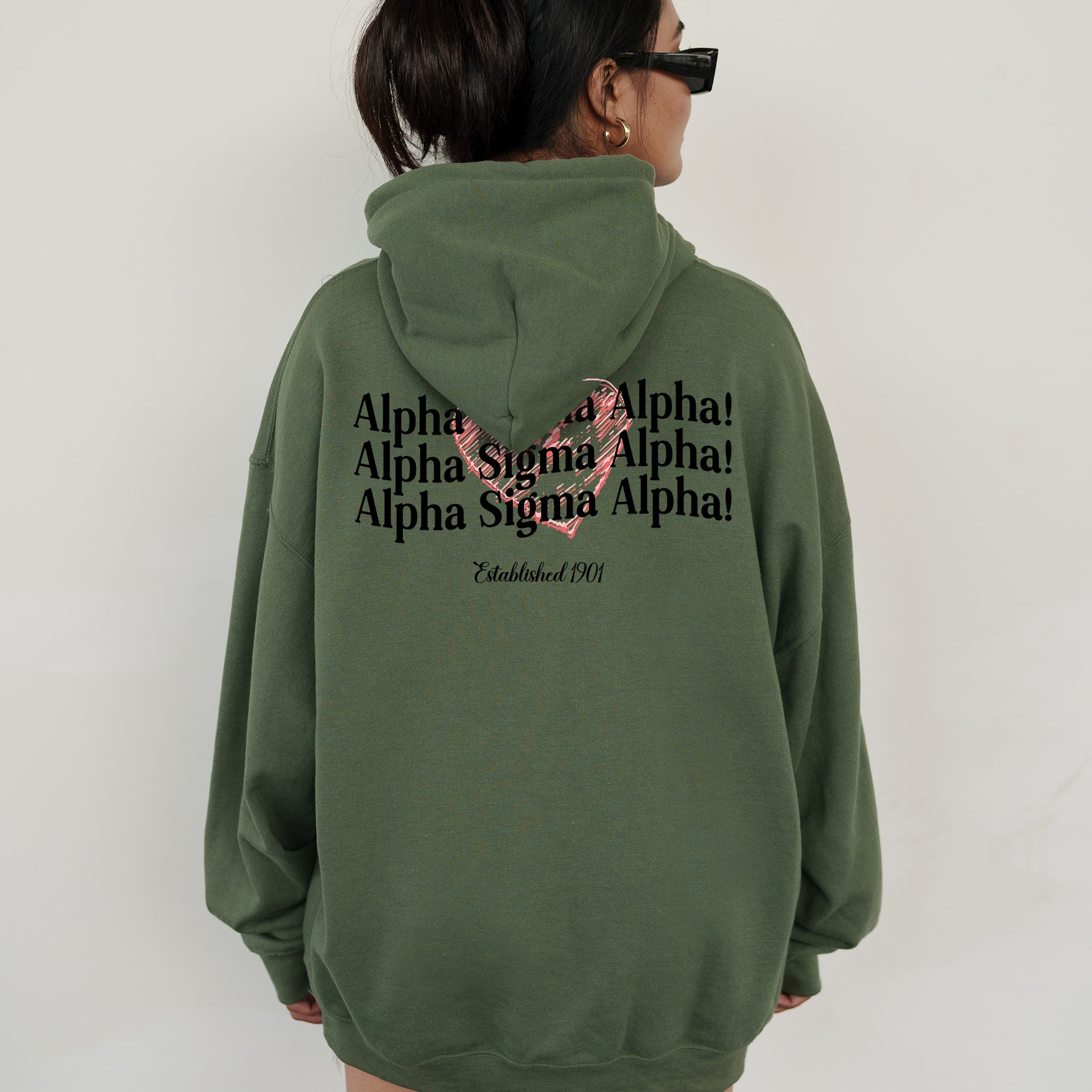 a woman wearing a green hoodie with a pink ribbon on it