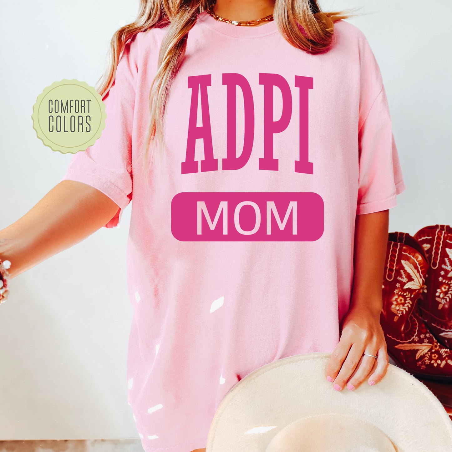 a woman wearing a pink shirt with the words adpi mom on it