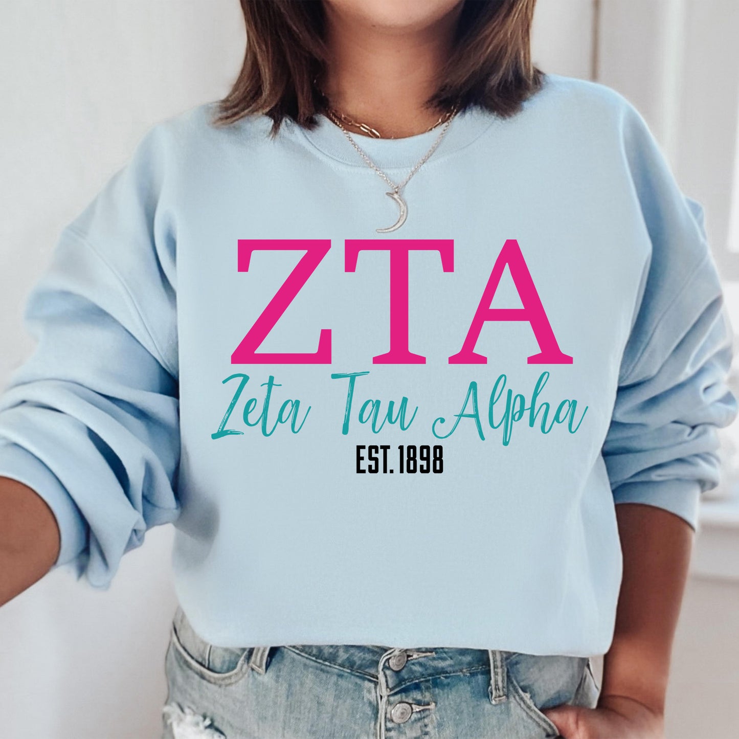 a woman wearing a blue sweatshirt with pink letters on it