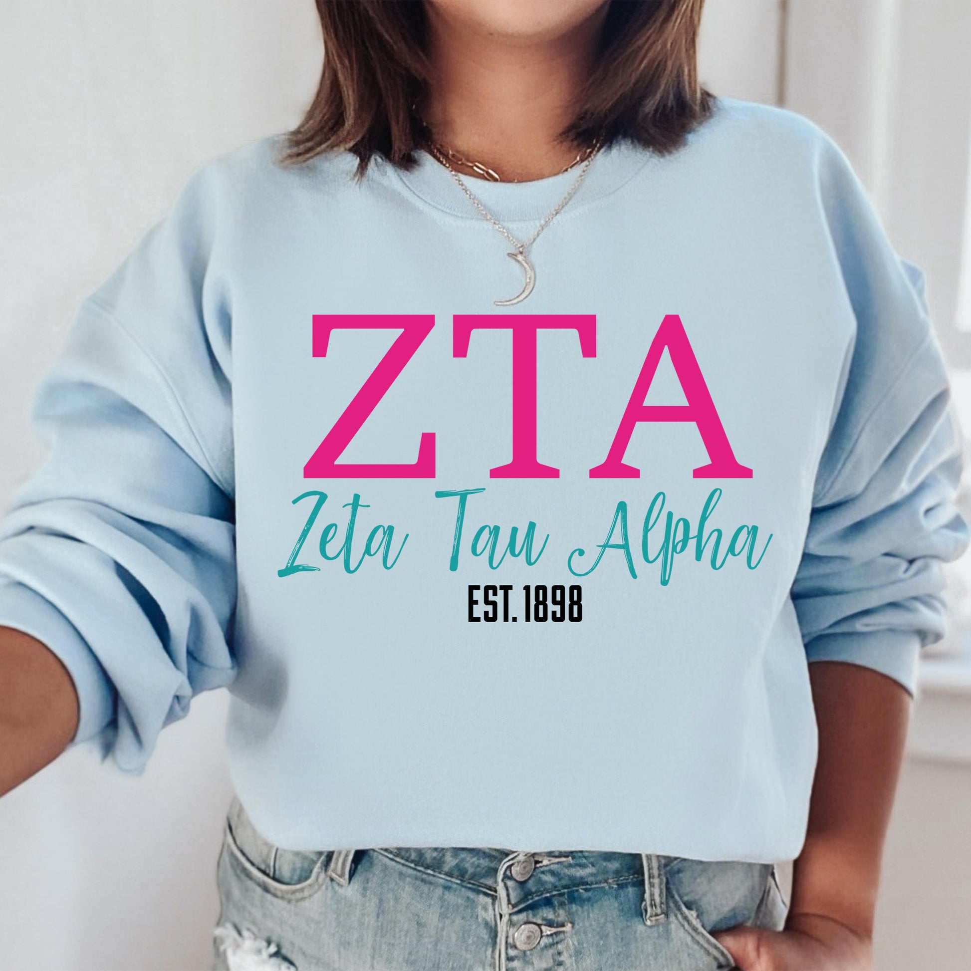 a woman wearing a blue sweatshirt with pink letters on it