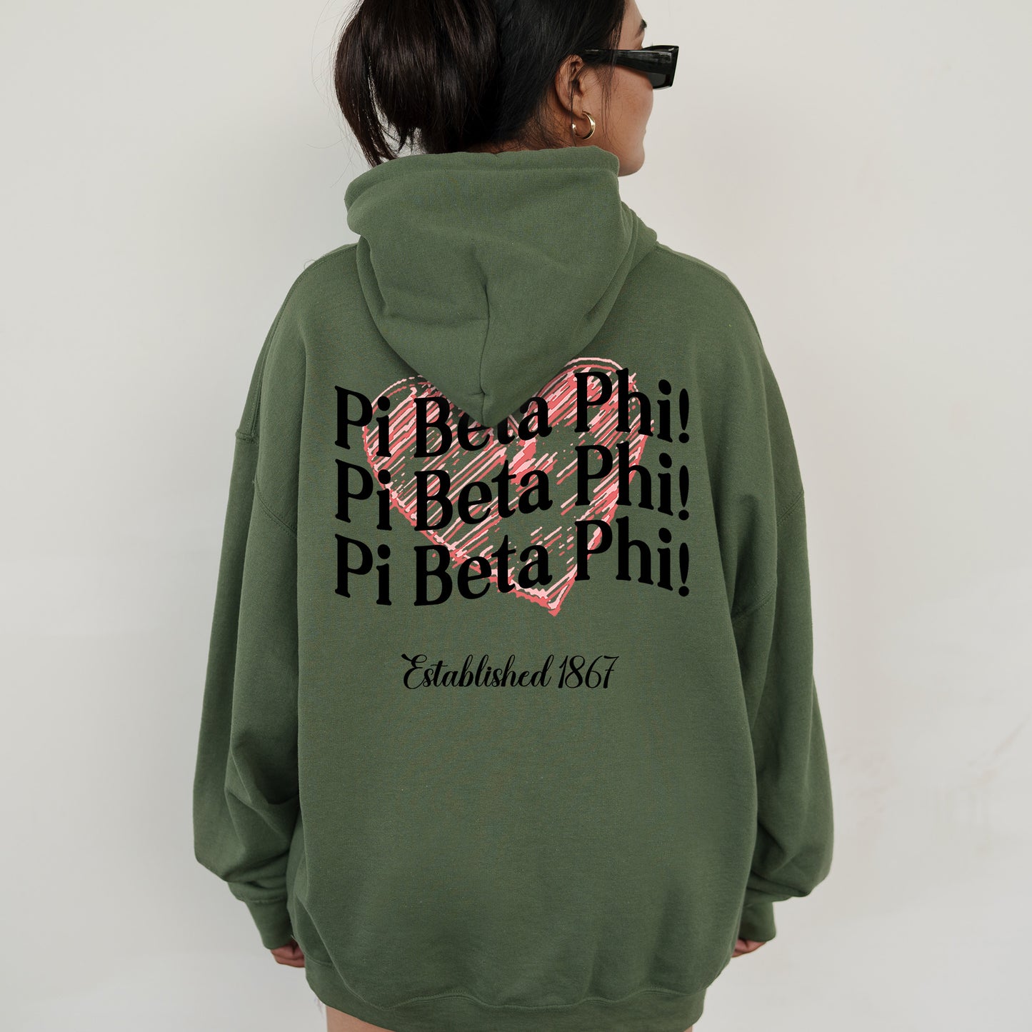 a woman wearing a green hoodie with a pink heart on it