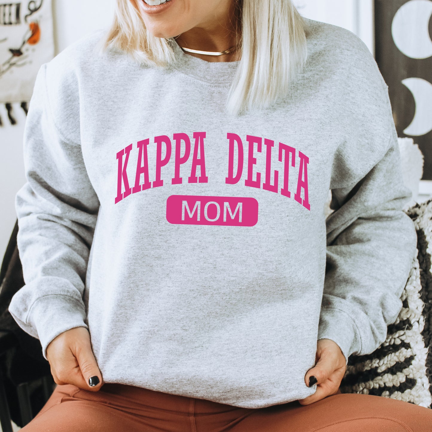 a woman wearing a sweatshirt that says kapa delta mom