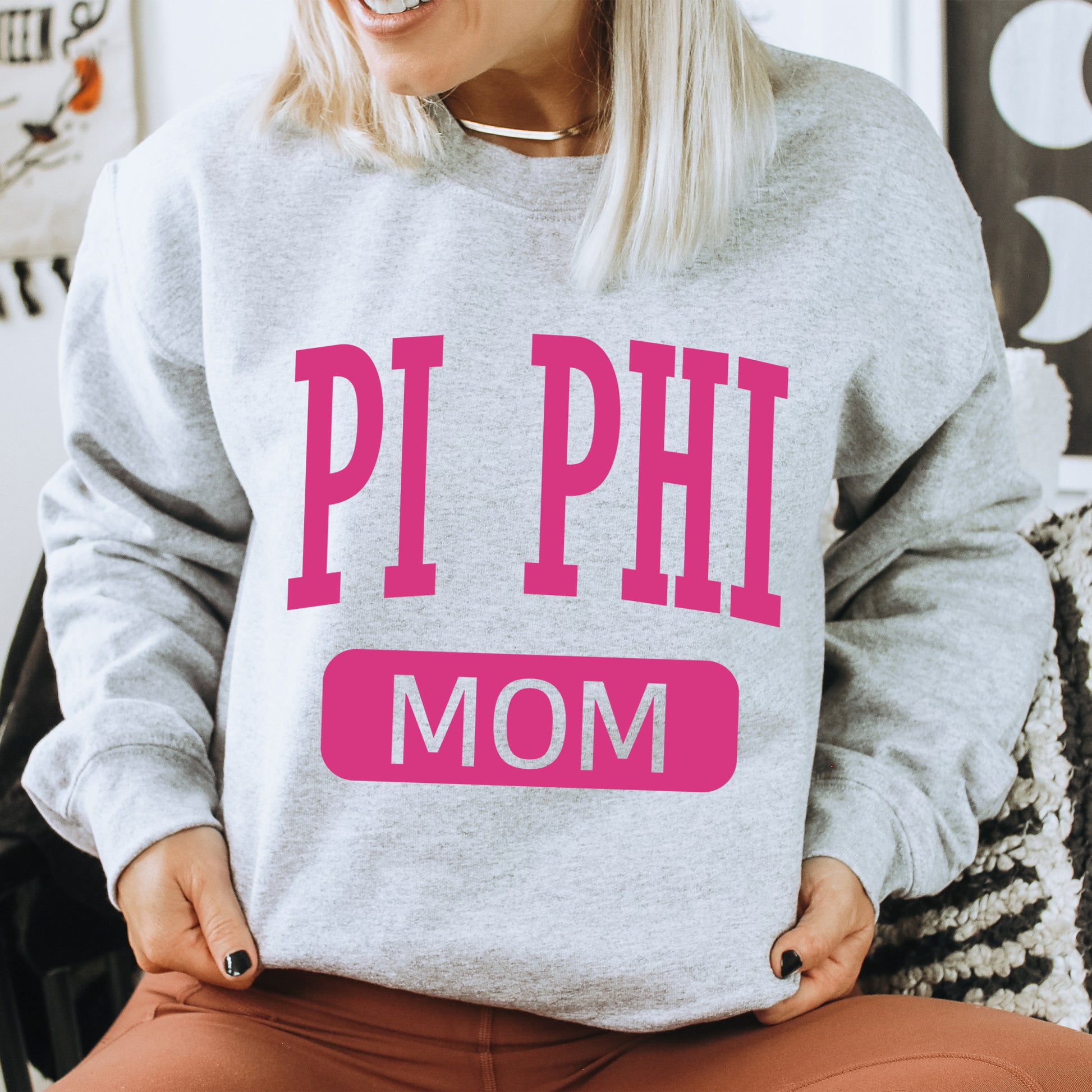 a woman wearing a sweatshirt that says pi phi mom