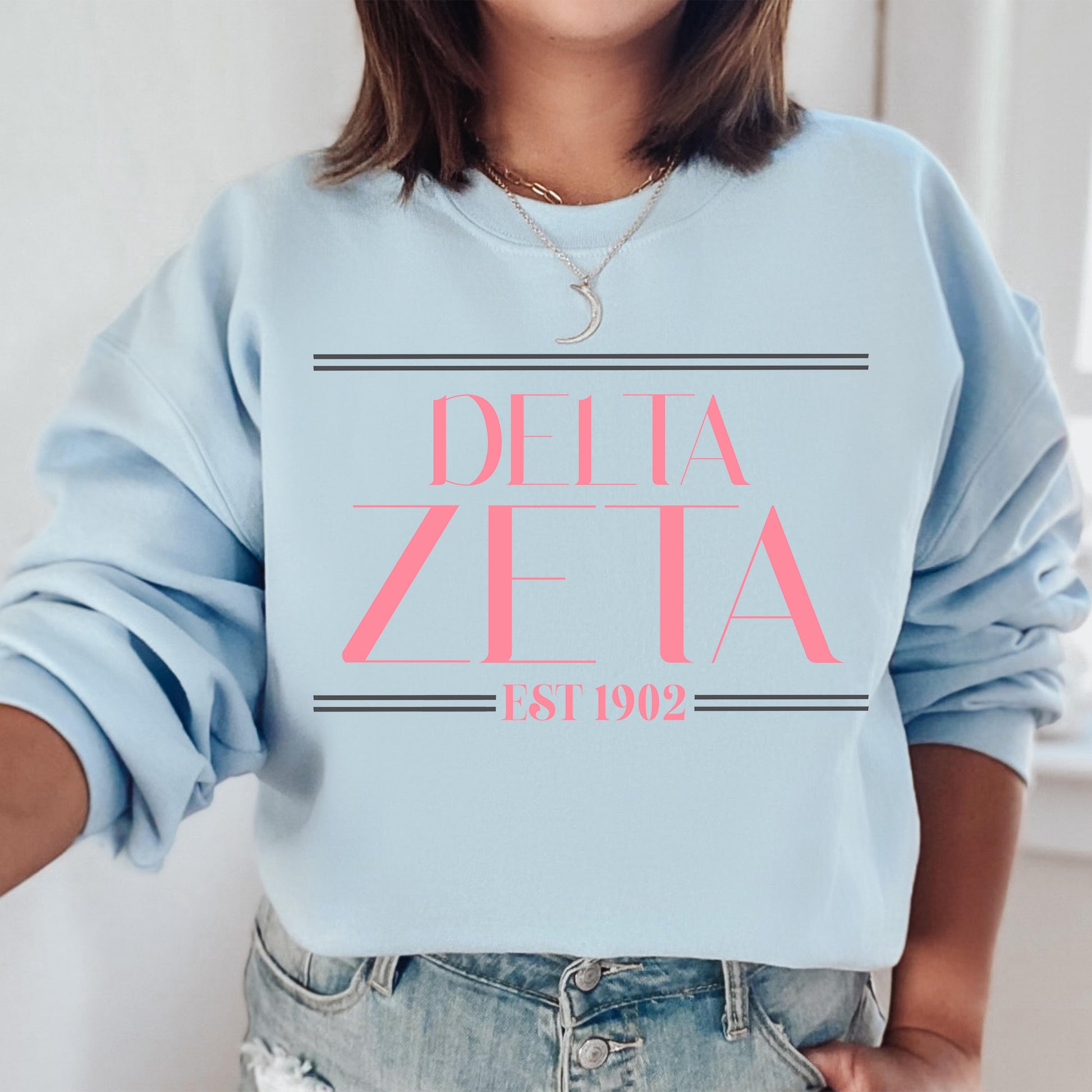 a woman wearing a blue sweatshirt with pink letters on it