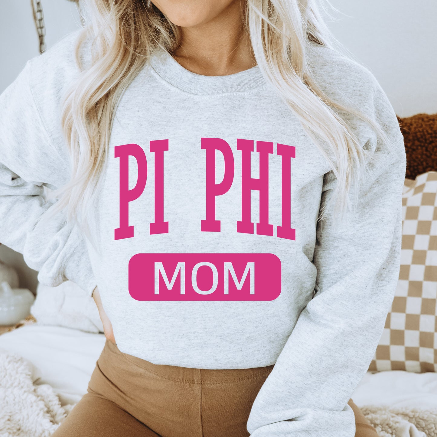 a woman wearing a sweatshirt that says pi phi mom