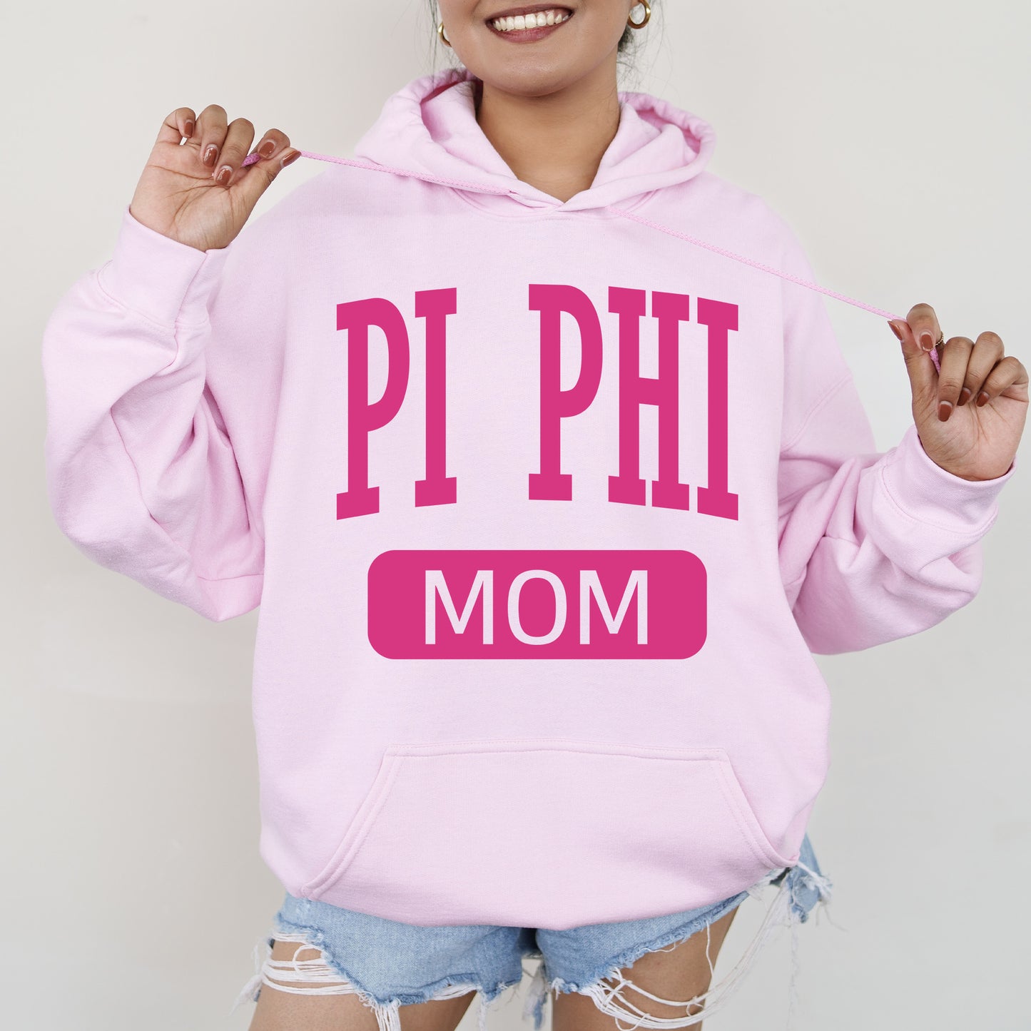 a woman wearing a pink hoodie that says pi phi mom