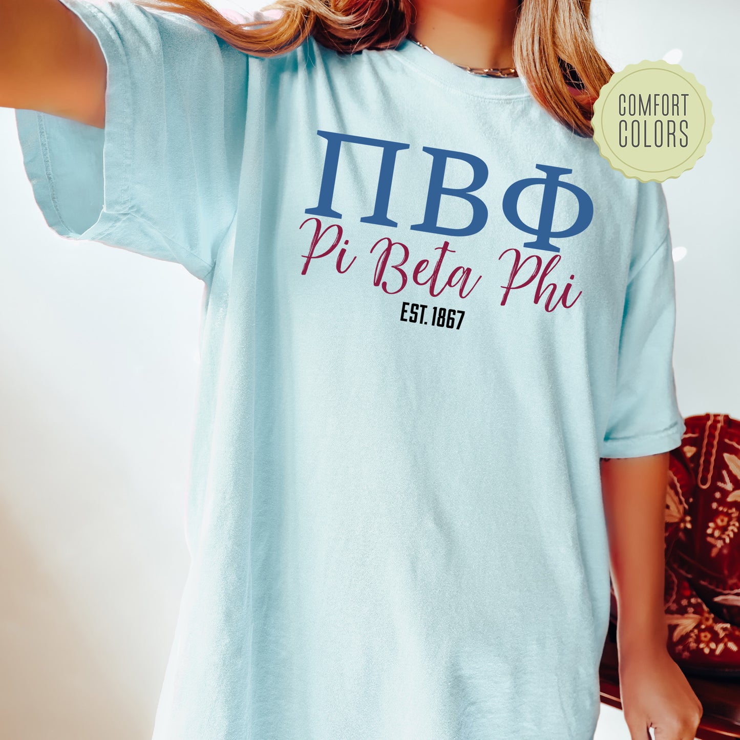 a woman wearing a blue t - shirt with the words pi beta pi est