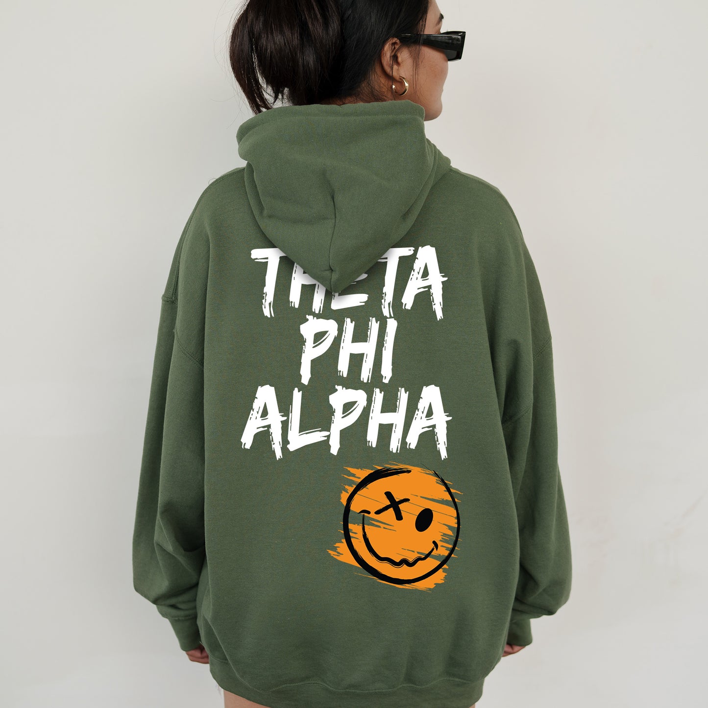 a woman wearing a green hoodie with a smiley face on it