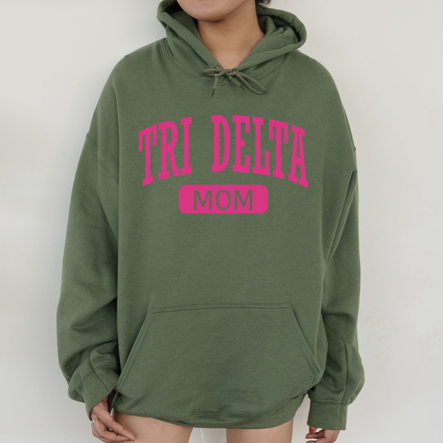 a woman wearing a green hoodie that says tri delta mom