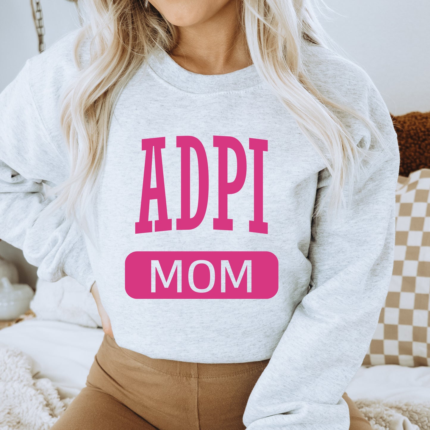 a woman wearing a sweatshirt that says adpi mom