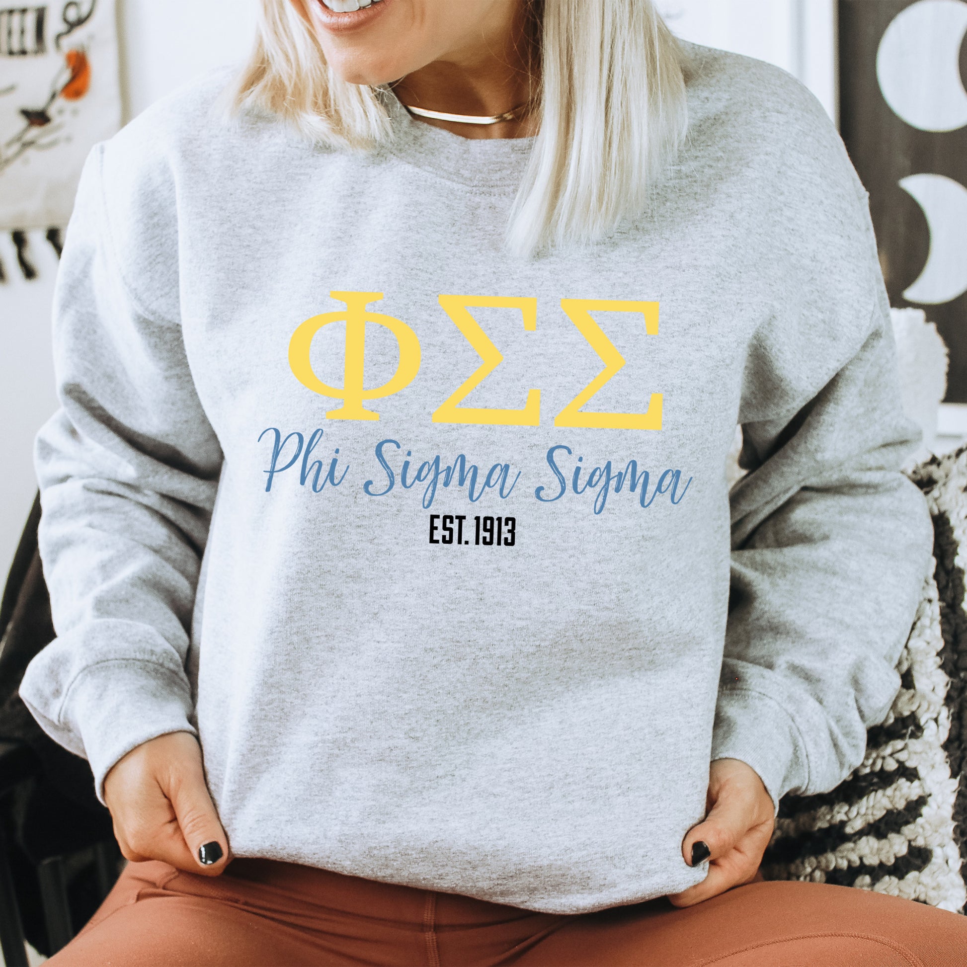 a woman sitting in a chair wearing a phi phi sweatshirt
