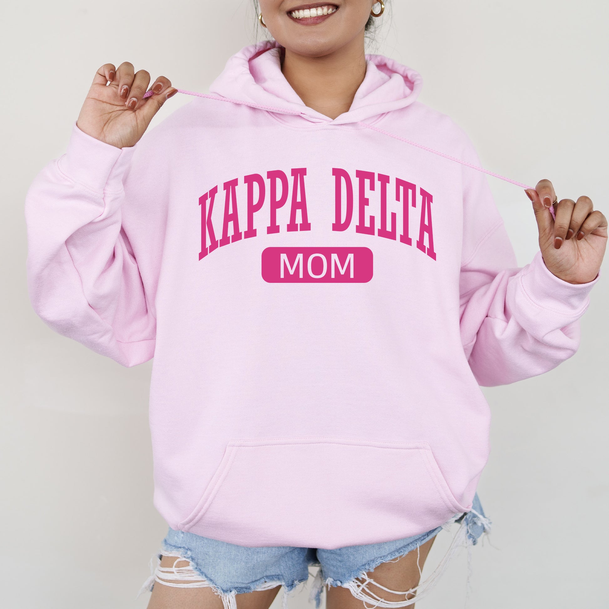 a woman wearing a pink hoodie that says kapa delta mom