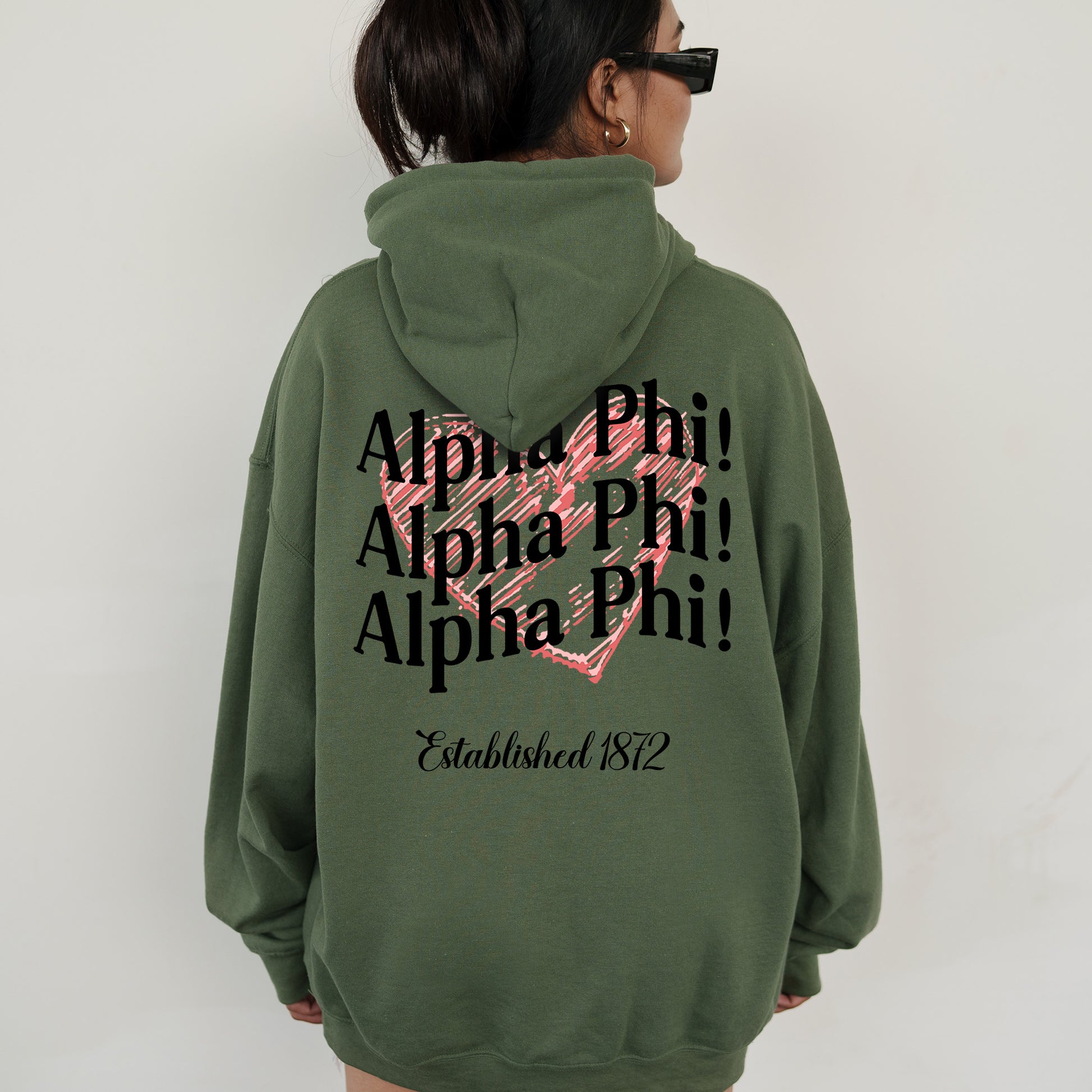 a woman wearing a green hoodie with a pink heart on it