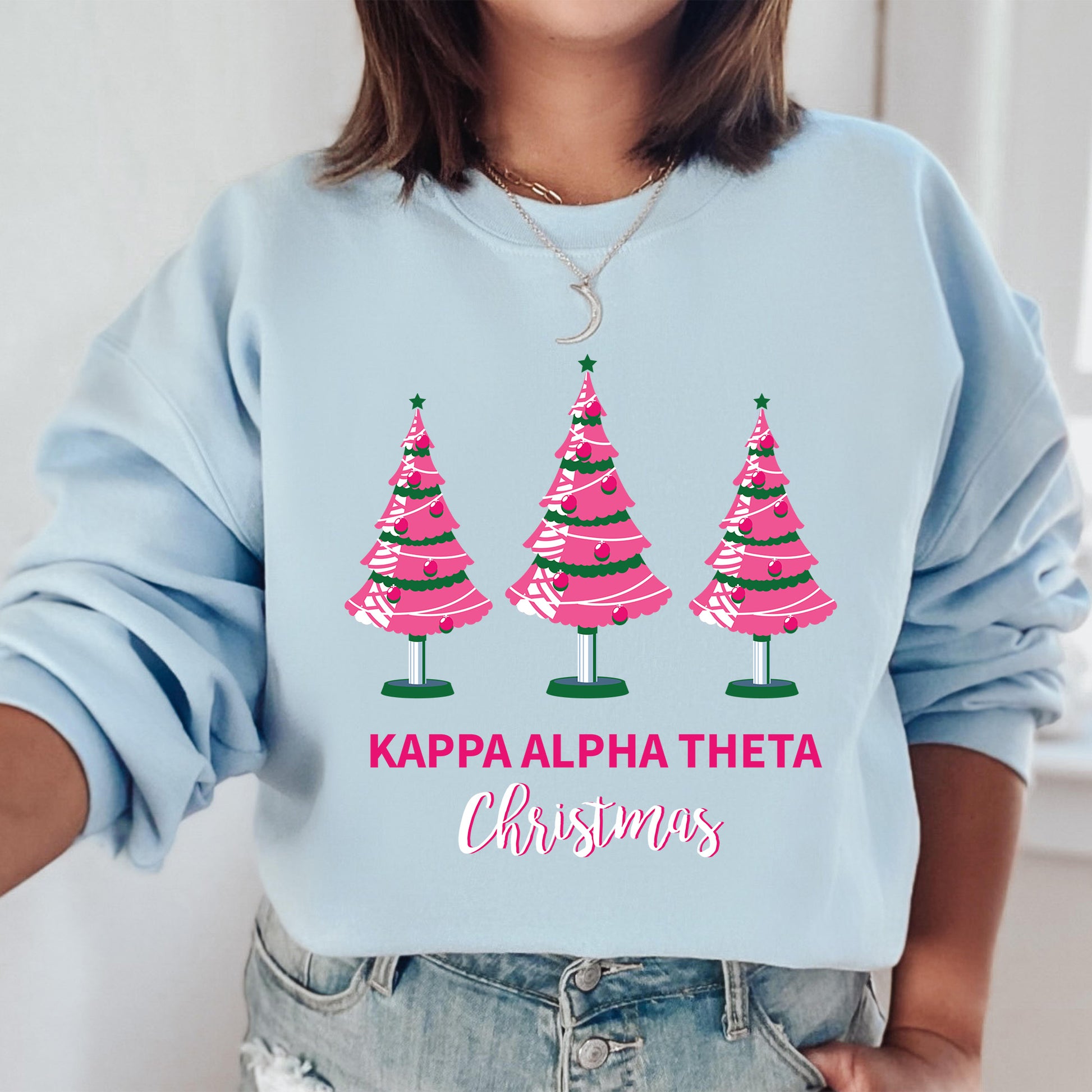 a woman wearing a blue sweatshirt with pink christmas trees on it